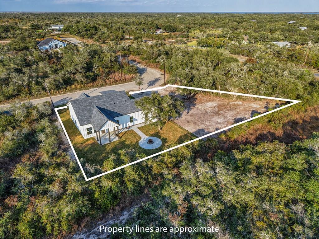 Experience coastal living at its finest in this brand-new 3 bedroom, 3 bathroom home located in the desirable community of Lamar Pointe Preserve—and the lot next door is included, providing the ideal space for a future boat barn, workshop, or added privacy. Step inside to an inviting open-concept kitchen and living area featuring a vaulted ceiling with wood-stained beams, durable tile flooring, and abundant natural light. The kitchen showcases a large island with stone countertops and accents, tasteful design elements, and a sink positioned perfectly beneath a window overlooking the tranquil outdoors. The primary suite is conveniently located on the main floor, offering a spacious bedroom, dual sink vanity, walk-in tiled shower, and a custom closet with built-in cabinetry. A guest bedroom and full bathroom with a beautifully tiled shower provide comfort and convenience for visitors or family members. Upstairs, a very spacious bedroom with its own ensuite bathroom offers endless possibilities—convert it into a bunk room, game room, or second living space to suit your needs. Outside, enjoy the coastal breeze on the covered back porch, gather around the cement firepit area, and take in the serene setting surrounded by mature trees, nature, and pristine wildlife. A two-car garage provides storage for vehicles, golf carts, and equipment. Located just down the road from the Lamar public boat ramp and Goose Island State Park, this home offers the perfect lifestyle for outdoor enthusiasts. Builder warranty included for peace of mind—don't miss this exceptional opportunity in one of Lamar's most sought-after new communities.