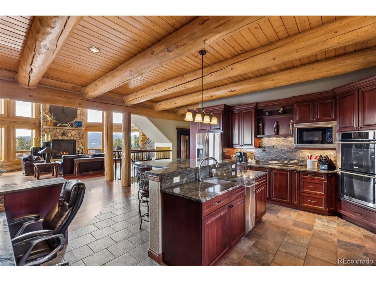 On 20 gentle acres in Golden Gate Canyon, this remarkable custom log home showcases expansive mountain views-from the Continental Divide to Pikes Peak, with Mt. Blue Sky anchoring the skyline and city lights shimmering to the east. The setting offers rare privacy and tranquility with easy access, just 30 minutes to Golden, and a short drive to Black Hawk and Central City. Inside, more than 5,400 square feet of thoughtfully designed living space blends mountain character with quality finishes. The great room impresses with soaring ceilings, exposed timbers, Brazilion cherry floors and a full wall of windows that capture the surrounding landscape and fill the home with natural light. The kitchen is built for everyday living and entertaining, featuring rich cherry cabinetry, generous granite counter space, a large island, polished slate flooring, and high-end stainless appliances-all opening to the main living area and its towering stone fireplace. A main-level primary suite offers comfort and convenience, complete with a spacious layout, gas fireplace, 5-piece bath with steam shower, a large walk-in closet, and direct access to outdoor living areas-perfect for quiet mornings with inspiring views. Four additional bedrooms provide ample space for guests and family, including two ensuite. A large loft adds flexibility for a home office, play space, or creative retreat. The lower-level family room features copper ceilings, a gas fireplace, and a gorgeous wet bar with an enclosed glass wine room. There's also space for a pool table, pinball, and media viewing. Outdoor spaces maximize the setting, with a large wraparound deck, plus a lower patio with outdoor fireplace leading to an expansive patio with fire pit; ideal for evenings under the stars. Four-car garage and adjacent flex/exercise room. Whether a full-time residence, mountain escape, or private executive retreat, this property delivers accessibility, privacy, acreage, and unforgettable views in a true legacy home.