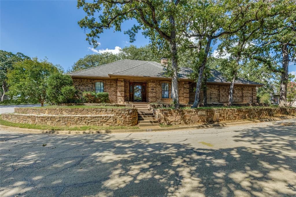Nestled amid large trees on cul-de-sac with partial views of Eagle Mountain Lake, this brick 3 bedroom, 2 bath home features a metal roof and iron fencing surrounding courtyards.  The kitchen has quartz countertops, real wood cabinets with built ins, and a breakfast nook with a raised accent wood ceiling.  The spacious family room with adjacent dining room will impress with vaulted ceilings, real oak paneling, a wet bar with sink, and a wood-burning fireplace. New, never lived on,  bamboo wood flooring was recently installed throughout much of the home.  A 16 Seer AC unit and garage mini-split ensure you stay cool in summer months. If you are seeking a lower maintenance yard that still offers the privacy of a single family residence in a quiet, adult neighborhood, then please schedule a showing now!  The location offers easy access to Hwy 199 from the Fort Worth side of Azle providing a quick commute to Fort Worth.   Survey is available. Title Work has been completed by Sewell Title.  Since photos have been taken, the yard has been professionally trimmed-landscaped.