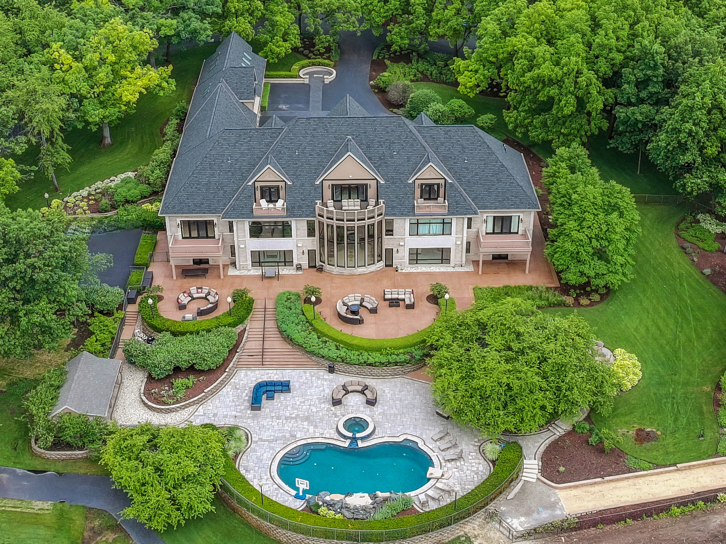 Glacier's End Mansion! A Once-in-a-Lifetime Opportunity to Own One of Illinois' Most Extraordinary Private Estates. Welcome to Glacier's End Mansion, an unrivaled move in and turnkey luxury estate encompassing more than 19.3 private acres of impeccably landscaped grounds. Following an extensive, multi-year and multi-million-dollar renovation completed in 2026, this remarkable property is one of the most sophisticated and comprehensively appointed residences ever offered in Illinois. Beyond one of two private gated entrances, a world-class estate unfolds. A private stocked lake, miles of paved trails, creeks, wildlife, a helipad, illuminated roadways, dramatic water features, manicured grounds, and resort-style amenities create an experience rarely found in a private residence. At the heart of the property stands a magnificent limestone and brick mansion offering over 23,000 square feet of refined living space served by two elevators designed to satisfy the most discerning buyer. The estate is handicap friendly, safety and security rivals some of today's most secure environments. A circular, illuminated drive accented by cascading waterfalls and fire features leads to a grand courtyard entrance where soaring ceilings and breathtaking floor-to-ceiling windows frame panoramic views of the lake and resort-style pool complex. Every detail reflects exceptional craftsmanship, including a new custom roof w/ copper accents, more than 200 new custom windows and doors, designer lighting, smart-home integration, 12 independently controlled heating and cooling systems. The estate's outdoor amenities rival those of a luxury resort. Enjoy a spectacular swimming pool w/ pool house featuring rock waterfalls, deck jets, diving board, underwater vacuum system, spa w/ fountain and sport jets, private sand beach, bocce court, basketball court, shooting range, walking and go-cart trails, helipad, expansive recreational grounds designed for both relaxation and entertainment. Inside, elegant formal and casual spaces blend timeless architecture w/modern luxury. The handsome library w/office showcases custom millwork, built-in bookcases, multi person custom desk, fireplace, concealed sliding doors. The grand living and dining rooms flow seamlessly into the breakfast area, gourmet kitchen, butler's pantry. Anchoring the kitchen is an extraordinary center island w/ seating for up to 16 guests, surrounded by extensive custom cabinetry and hidden storage solutions. Dramatic oval & straight overlooks w/ custom glass railings ascend through the home, creating a striking architectural centerpiece. The luxurious primary suite serves as a private retreat, featuring lake and pool views, French doors to a private balcony, dual custom dressing rooms, wet bar, a spa-inspired bath w/ soaking tub, oversized shower. Four additional ensuite bedrooms are arranged around a central private gathering space that enjoys access to multiple balconies, overlooking the grounds, lake, and pool. This space also has a stocked wet-bar w/counterspace, appliances. Two separate guest or staff residences provide exceptional flexibility for extended family, guests, or household personnel. Each separated w/a grand foyer, private access. Additional amenities:13 bathrooms, Multiple storage rooms, Pool House, 4 kitchens, Banquet kitchen, entertaining areas, Massive fitness center, Indoor hot tub,10-15 person sauna, Red light therapy room, Home theater w/ Dolby Atmos surround sound, Wine room, Game rooms, Central entertainment bar, Multiple laundry facilities, commercial-scale laundry room, Security operations center, Communications room, Panic rooms, Extensive mechanical and utility infrastructure, Heated/cooled garage space for approximately 25-30 vehicles, RVs, vehicle museum showroom. Representing an investment estimated to exceed $30 million to replace. Glacier's End Mansion offers an extraordinary opportunity to acquire a truly turnkey estate at a fraction of its replacement cost.