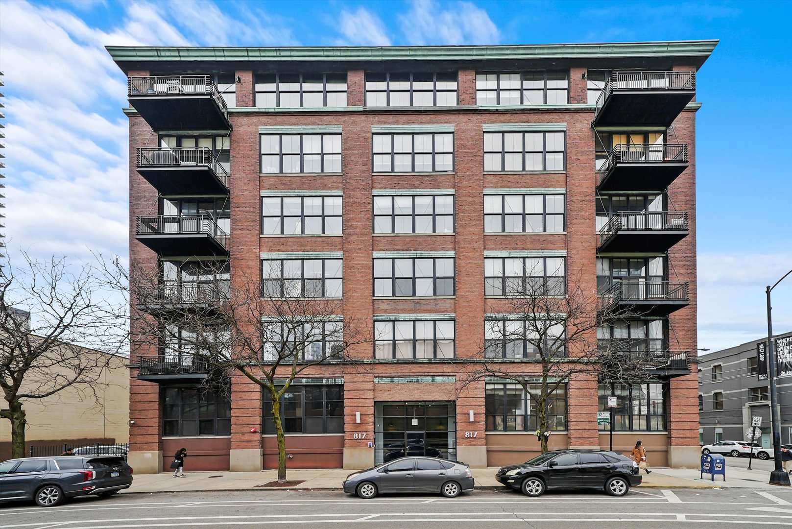 Welcome to this stunning, sun-drenched 2-bed, 2-bath loft-style condo in the highly sought-after Washington Blvd Lofts. Blending historic charm with modern sophistication, this West Loop gem features soaring 12-foot ceilings, exposed brick, and oversized 8-foot windows that flood the space with natural light. Following a luxury renovation in 2023, the home features custom-built details throughout, creating a truly one-of-a-kind living experience.  Step inside to discover a beautifully updated kitchen with refinished cabinetry, new hardware, a sleek backsplash, and statement lighting fixture above the island. The open-concept living and dining area is anchored by a striking fireplace buildout with integrated uplighting, drawer storage, and an electric drop for seamless TV mounting-perfect for cozy nights in.  The primary suite is a tranquil retreat, featuring a stylish accent wall, plush carpeting, custom closet build-out, sconce lighting, and a bespoke sliding door for added privacy. The second bedroom offers versatility with a custom wardrobe build-out, elegant sconce lighting, and a sliding door installation with sophisticated millwork. Both bathrooms have been tastefully appointed with sleek tilework and seamless glass showers.  Additional highlights include a dramatic foyer with perimeter accent lighting, a statement wallpaper feature, and a custom millwork feature wall that flows effortlessly into the main living space. Step outside to your expansive west-facing balcony, ideal for enjoying breathtaking sunsets and city views.   This well-maintained, professionally managed building was converted in 2000 and offers optimal comfort with 15 inches of concrete between floors. Included in the price is a spacious storage cage (#507, located on the first floor) and a secure outdoor deeded parking space (#21).  Ideally located in the West Loop, this home is steps from Mary Bartelme Park, with a dog park, play area, and farmers market. Enjoy easy access to Mariano's, Whole Foods, Target, and local markets. Foodies will love the proximity to Restaurant Row, Fulton Market, and Madison Street's boutiques and bistros. Commuting is effortless with access to I-90/94, I-290, Metra, and CTA.