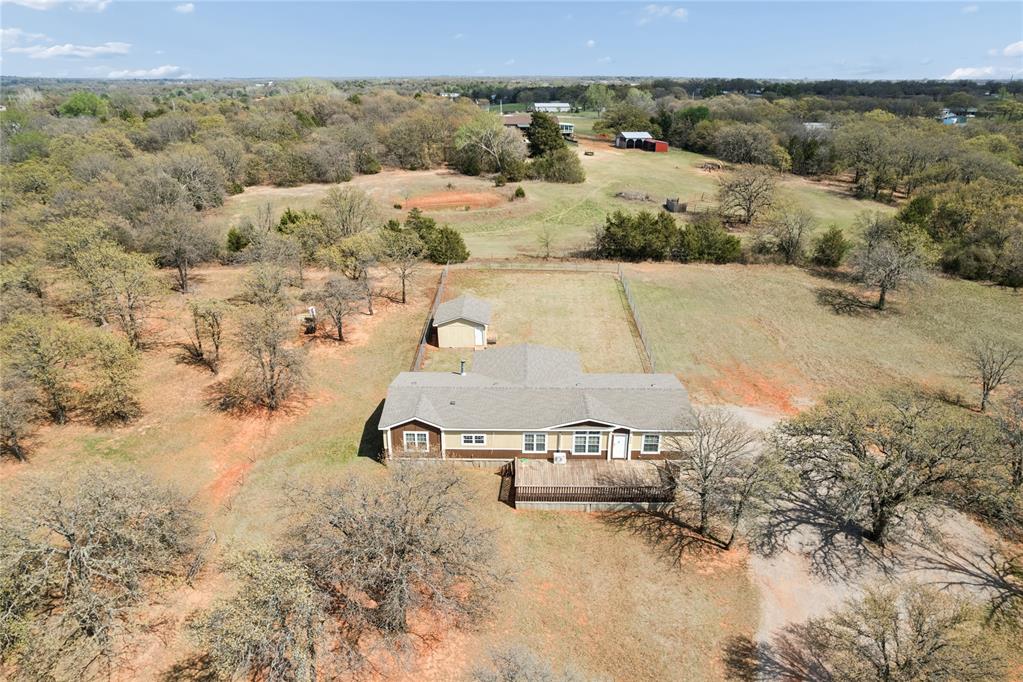 Welcome to this well-maintained 2013 manufactured home offering approximately 2,270 sq ft with 4 bedrooms, 2 baths, and 2 spacious living areas. This property is perfectly set up for country living and horse enthusiasts, featuring a 30x60, 8-stall horse barn with tack room, wash rack, and two 12-ft roll-up doors with openers. The land includes 3 large fenced pastures and 3 paddocks with shelters and water, plus a fully fenced yard with a 10x20 storage shed and an additional large storage shed.Inside, you’ll find a warm and inviting interior with tile flooring and wood-look tile in main areas, carpet in the bedrooms, crown molding throughout, and beautiful stone and wood accents. Natural light fills the home, enhanced by accent wall lighting. The living area features a wood-burning fireplace with a stone hearth, creating a cozy focal point.The kitchen offers a large island, breakfast bar, custom cabinets, plenty of storage, vent hood, garbage disposal, canned lighting, and a stylish utility chandelier. A nicely sized dining area sits just off the kitchen, ideal for gatherings. The large laundry room includes cabinets, pantry space, and a sink for added convenience.The primary suite includes a spacious bedroom and a private bath with dual vanities, garden tub, separate shower, private toilet area, and a large walk-in closet. Three additional bedrooms offer standard or walk-in closets, and the guest bath features a tub/shower combo with venting.Enjoy outdoor living with a large covered deck, back porch, and additional wooden deck. Additional features include double-pane windows and two AC systems. A rare, move-in ready property combining comfort, functionality, and a complete horse setup.