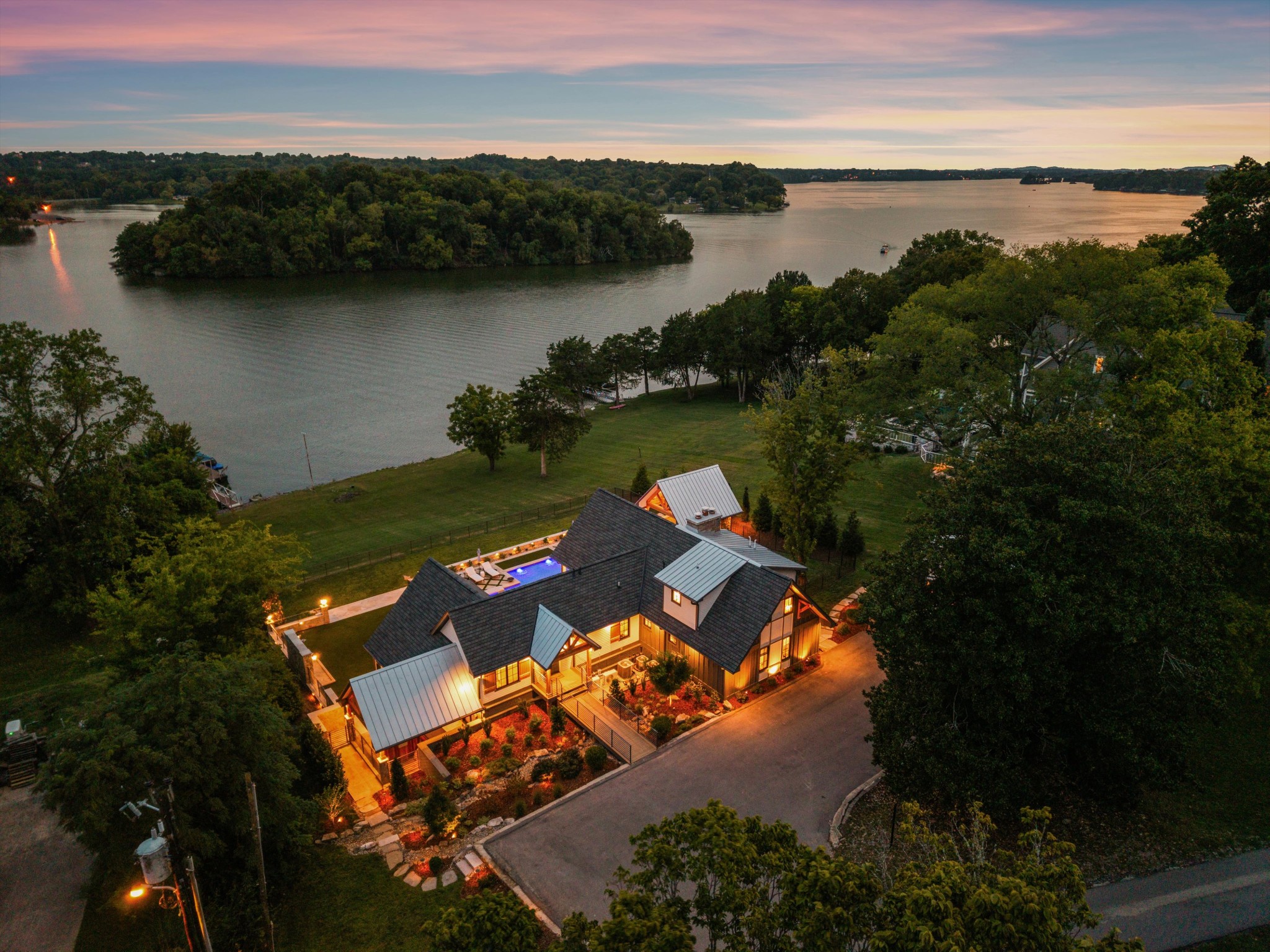 An Extraordinary Private Resort on Old Hickory Lake - Less than 30 minutes from Nashville, this extraordinary waterfront lifestyle unfolds along approximately 150 feet of coveted Old Hickory Lake shoreline. Completely reimagined in 2024, this architecturally designed residence blends sophisticated interiors, resort-caliber amenities and life on the water. Walls of sliding glass open to panoramic lake views for effortless indoor-outdoor living. The chef’s kitchen pairs quartzite surfaces with a complete Miele suite, paneled refrigeration and built-in coffee system. Custom cabinetry, a sun-filled dining room with beverage bar, two fireplaces, electronic shades, Sonos audio and Josh.ai smart-home technology elevate everyday living. The private primary suite features a tiled walk-in shower, TOTO fixtures and custom wardrobe cabinetry. Two additional bedrooms, bonus space and a finished lower-level club room with entertainer’s kitchen and full bath welcome family and guests. Outdoors rivals a private resort: a Waterscapes-designed pool with integrated spa, fire bowls and water features, manicured turf, fire-pit gathering area, outdoor shower and cabana with Viking grill and beverage centers. Covered outdoor living with integrated heaters extends the season. A dedicated wellness center with cold plunge and Rocks sauna, plus an elite performance fitness studio outfitted with Arsenal Strength, UMAX and Rogue equipment, makes wellness part of the lifestyle. At the water’s edge, a private dock with boat lift, jetport and lounge deck embraces boating, swimming and sunsets as a part of everyday life. The detached carport with flexible studio space offers an inspired setting for creatives or guests. Whole-home AV, Josh.ai controls, iAquaLink pool automation and dual tankless water heaters complete this exceptional residence—created for the discerning buyer who values design, privacy, wellness and direct access to the water.