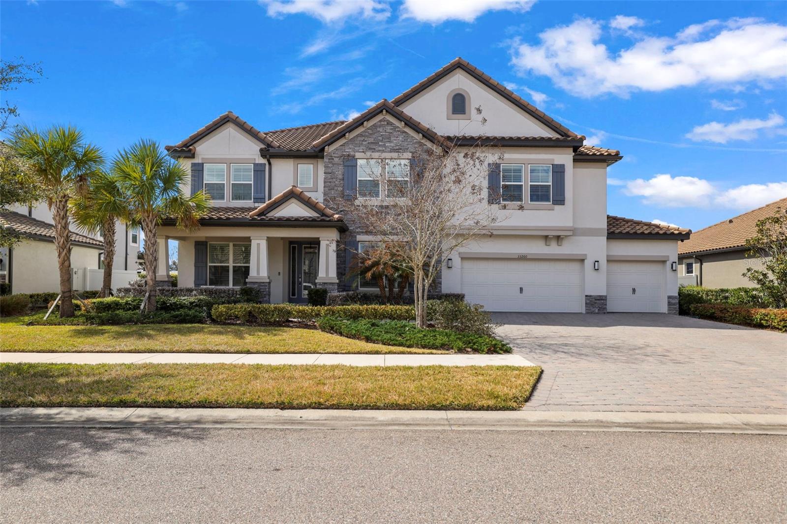 Stunning and well maintained grand residence with an abundance of luxurious features and upgrades in the gated Graybrook neighborhood of the WaterGrass community. This exquisite six-bedroom, four-bath, five-car garage pool home is a craftsman masterpiece and was built in 2022. This property boasts a generous 4,773 square feet of living space with an extremely well-designed floor plan including an office, an enormous bonus loft and multiple flex areas. The home’s stone accented exterior elevation exudes timeless sophistication, welcoming you with a grand entrance and open porch. Inside, motorized shades in the living area provide effortless control of natural light while enhancing the ambiance. The living area features gorgeous wood and porcelain accented feature wall with a built-in electric fireplace, creating a focal point that is cozy and stylish. The gourmet kitchen is a chef's delight, showcasing an oversized dual waterfall quartz island that is visually striking. The large walk-in pantry offers plenty of storage, while the dry bar with a beverage refrigerator serves as a coffee bar, and built-in GE Profile convection oven and microwave provide convenience and elegance for entertaining guests. The GE Profile electric cooktop with a range hood, white subway tile backsplash, hidden cabinets under the bar, and smart and touch-activated inlayed sink are just a few of the distinctive features this kitchen has to offer. Additionally, an extra butler's pantry provides added convenience for preparing meals and hosting events. Indulge in luxury in the primary suite, offering dual walk-in closets and a spa-like haven for a primary bedroom, complete with a water closet, a generous linen closet, a frameless glass walk-in shower, a separate deep soaking bathtub and a split dual vanity with makeup counter. Entertain in style with the large media room, with surround-sound speakers, and a high-quality projector screen for a true cinematic experience. The oversized loft at top of the stairs offers additional flexible space or relaxation zone. The property boasts ample custom trim and millwork, including crown molding, tray ceilings and feature walls, adding a level of refinement throughout the home. Upgraded LED recessed lighting, hanging light fixtures and plumbing fixtures complement the elegant design, creating a warm and welcoming atmosphere. Step into the backyard, and you'll find an oasis, providing year-round relaxation and recreation with the screened-in heated saltwater pool boasting three cascading waterfalls and two elegant fountain jets. Lounge in style on the two tanning ledges, each with removable umbrellas, or unwind in the luxurious spa after a long day. Enjoy privacy and security in the sprawling fully fenced backyard, providing a safe environment. The rare five-car garage with hanging storage and a convenient workbench is perfect for the car enthusiast or anyone in need of ample storage space. Located in the gated Graybrook neighborhood of the WaterGrass planned community offering additional amenities and community pool, as well as Watergrass Elementary School and fire department. With nearby interstate access, this growing area has the sought-after Innovation Preparatory Academy and Kirkland Ranch Academy of Innovation while close to shopping and dining of the Tampa Premium Outlets and Shops at Wiregrass.