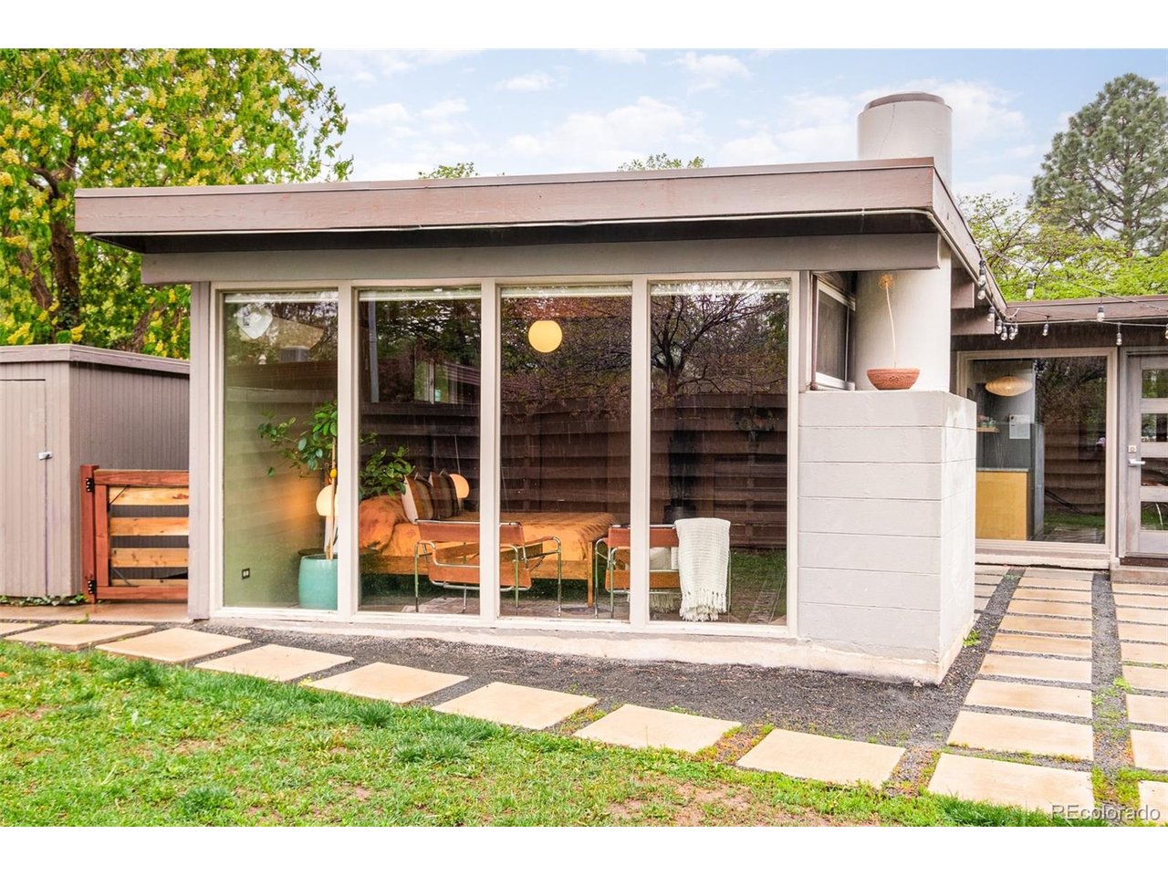 Welcome to the Kern House, an exceptional example of Usonian modernism in the legendary Arapahoe Acres neighborhood. This is a rare opportunity to live inside a piece of Denver's architectural history, as this was the first mid-century modern neighborhood to be listed in the U.S. on the National Register of Historic Places, and it remains a tight-knit community coveted by mid-century modern lovers nationwide. Organic materiality defines this home with tongue-and-groove ceilings with exposed wood beams, warm mahogany woodwork throughout, and beautiful slate tile work. Floor-to-ceiling windows create a strong indoor-outdoor connection, flooding every room with abundant natural sunlight. A recently remodeled kitchen (2024) blends modern convenience with the home's original design. Originally designed by neighborhood architect Edward Hawkins, the home boasts a spacious family room addition that Hawkins later also designed himself in the mid-century. The primary bedroom is spacious, warmed by a new gas fireplace, and framed by a striking wall of floor-to-ceiling glass windows overlooking the backyard. The furnace, AC, water heater, and windows have all been updated in the last five years.Outside, the private yard continues to reflect modernist design principles with concrete pavers, mature trees, and a fire pit made for cool Colorado evenings. A 1-car attached carport completes the property, next to the home's signature orange gate. This home is more than just a place to live. It's a preserved piece of design history, ready for its next steward. Conveniently in south-central Denver, minutes from Swedish Medical Center, coffee shops, and more.