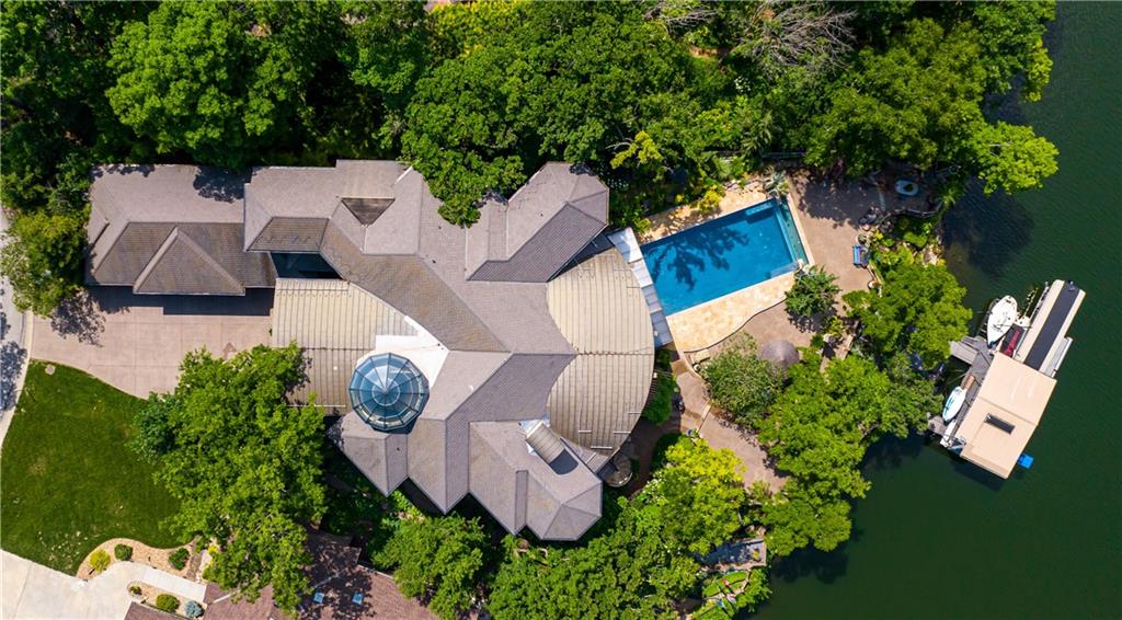 With an expansive lake front view, this home was designed for grand-scale entertaining yet tranquil retreat living.  A museum-worthy 1,000 bottle wine room and glass dome-topped, free-floating 3 story spiral staircase greet you upon entering custom front doors. Prepare to be wowed by a 26-foot barrel wood ceiling, extending thru the home, and 900-gallon living reef, saltwater aquarium. High-end finishes/fixtures throughout include natural stones, rare woods, Labradorite main kitchen countertops, and hand-blown glass Chihuly chandelier. Stunning architectural ceilings include one-of-a-kind dining room ceiling - truly a work of art. Private Primary Suite hallway with marble mosaic floor, beverage bar, and stairway to the library & gym/spa. Suite includes fireplace, home theater system, steam shower, and deck access. Telescoping enclosure enables year-round use of infinity-edge pool. Lovely al fresco deck-dining with outdoor kitchen, custom granite 22-person table, fireplace, TV, & lake views. Indoors connects to outside via LL bi-folding doors,  spa room and deck staircase. Lush, extensively landscaped grounds include gas torches, fountains, waterfalls, lighting, & integrated, computer-driven bug suppression system. Double boat dock with 4 hydro lifts. Appreciate the convenience & comfort of a 5 stop/2 door elevator, the latest smart home integrated system, 2 laundry rooms, dog shower, greenhouse, back-up generators, and heated driveway, steps, deck, main & lower-level European limestone floors. Midwestern-friendly, the Lake Winnebago community and well-stocked, 400-acre lake include many amenities. Why vacation at the lake when you can live the lifestyle every day? Home located less than 30 min from KC, in Lee's Summit school district.