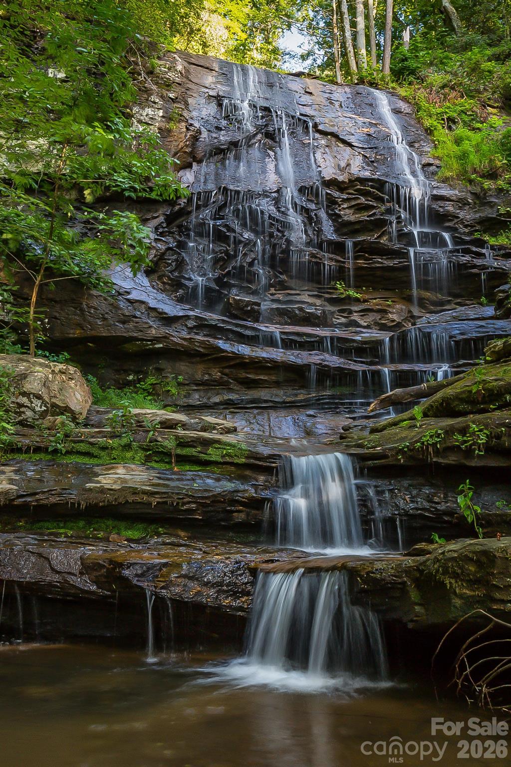 *Not all luxury is built - Some of it is discovered! Here, every movement feels intentional, every vista earned!!!*An extraordinary opportunity awaits—over 60+ acres of infrastructure-ready land anchored by one of the most compelling natural features in Western North Carolina: your OWN PERSONAL/PRIVATE ±175-foot WATERFALL, cascading through the heart of the property and setting the tone for a sanctuary that is both powerful and serene!!! The sound of moving water, the stillness of the forest, and the privacy of the land create a sense of calm that is increasingly difficult to find - if at all for these personal features, VIEWS and privacy with the acreage - for this price!!! This is far more than a mountain tract - It is a rare convergence of scale, water, elevation, and readiness—a setting where sweeping, unobstructed mountain views frame a landscape shaped by flowing creeks, quiet forest paths, and dramatic changes in terrain. ~~~Private trails invite exploration—leading to sandy-bottom streams, shaded "swimming/wading" holes, and the WATERFALL itself, where a natural rock ledge forms a cooling cascade and an UNFORGETTABLE sensory EXPERIENCE!~~~Beyond the waterfall, the property features a tranquil man-made pond, meandering creeks, abundant wildlife, and multiple cleared homesites, each thoughtfully positioned to offer privacy and commanding outlooks. The foundation is already in place: underground power and water access are installed, allowing you to move directly into the building phase—whether your vision is a refined mountain retreat, a contemporary glass residence, or a collection of cabins designed for family, guests, or legacy use.Properties of this caliber—especially those defined by water, views, and readiness—are exceptionally difficult to replicate at any price point. This is a land offering that must be traveled, heard, and felt to be fully understood!Notable Features:• Private ±175-foot waterfall—rare, dramatic, and entirely yours• Over 60+ acres of diverse, usable terrain w/ ability to buy up to 100+/- adjacent acres off Shoal Ridge Lane• Pond, creeks, trail system, and natural recreation areas• Multiple cleared homesites with long-range mountain views!• Underground power in place; water available• Privacy and peace of mindAdditional acreage up to almost 100+/- and unique features such as a personal CAVE accessible by a trail may be available by request on Shoal Ridge Lane - including not only access to a private natural cave, expanded homesites, and extended mountain views—with the potential to combine into a much larger legacy holding!!!This tract balances seclusion with accessibility. Enjoy proximity to everyday essentials while remaining centrally positioned—approximately one hour to Asheville or Greenville/Spartanburg, 1.5 hours to Charlotte, and just minutes from Lake Lure, Chimney Rock, and Hendersonville for dining, recreation, and seasonal events.~~~Proof of funds or pre-approval required prior to touring. Agent-accompanied showings only.~~~
