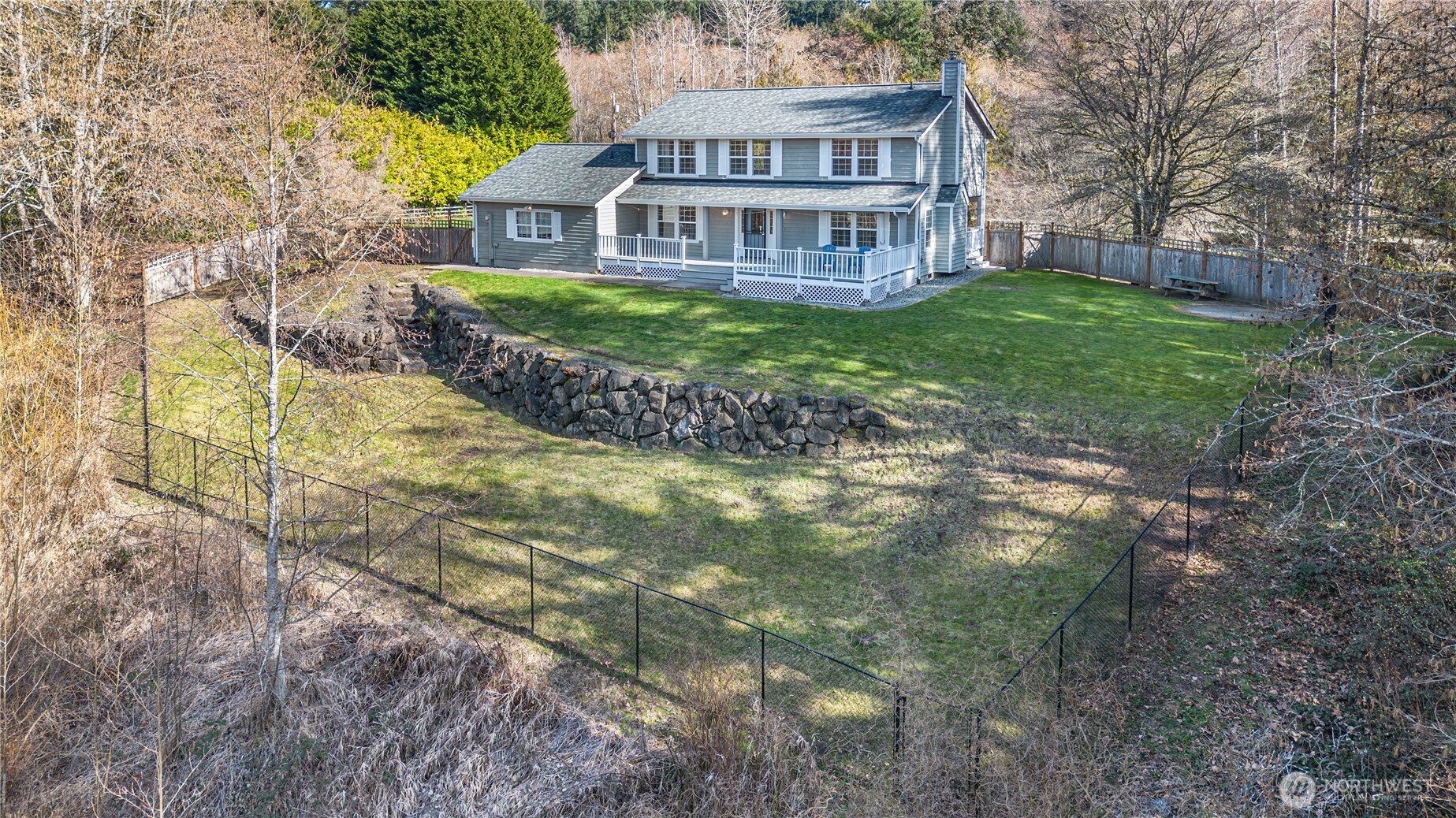 Welcome to sunny Dogwood Hill, a peaceful 5-acre retreat surrounded by natural beauty. Two graceful dogwood trees bloom on the property, joined by a variety of mature trees and fruit trees that create a private, park-like setting. A trail circles the perimeter for daily strolls, and a gentle creek adds to the serene atmosphere. The terraced yard offers wonderful outdoor spaces, including a pool pad ready for summer enjoyment and a handy shed for storing yard tools and equipment.  A private well and septic system help keep utility costs low.    Inside, this spacious home features 4 bedrooms, 2½ baths, and a dedicated den or office—ideal for remote work or creative pursuits. The kitchen is designed for gathering, complete with two islands so everyone can cook, prep, and connect together. Take in the views of your land from the expansive front deck made of Trex decking, or unwind on the covered porch off the kitchen while listening to the soothing sounds of our spring rains.  Recent updates include a roof and gutters replaced in 2024, new carpet in the living room and window coverings in 2022, plus dishwasher and microwave.  Located just 1.75 miles from the Kingston ferry terminal, this property blends tranquil country living with commuter convenience.  Come see this spectacular home before it's gone.