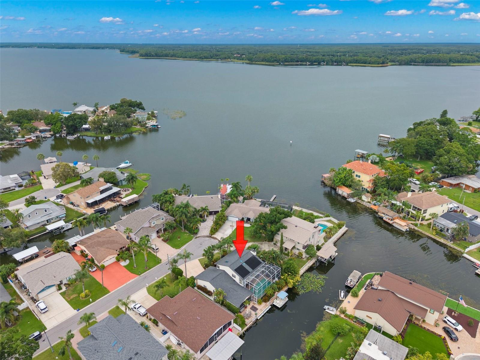 LAKE TARPON - right out your back door!!  A 2,500 acre, fresh water lake known for excellent bass fishing, boating, water skiing.  Moor your boat at your backyard deck/dock in a protected canal & enjoy all the lake benefits & fun!  This peaceful, residential setting provides a perfect backdrop for your own 'resort' oasis.  Float around in the solar heated pool, relax & unwind in the hot tub, watch movies from multiple pool lounge/seating areas, enjoy drinks & food at the poolside dining tables or star gaze amidst soft, perimeter pool lighting.  The 'heart' of this home is the open concept 'gallery'.  At one end, a wood burning fireplace quietly glows, then seamlessly intertwines with the dining area & wet bar, finally transitioning into a culinary delight!  Chef's kitchen includes extensive wood cabinetry, matching quartz counters & backsplash, bar seating, coffee/side bar, double ovens, butler's pantry.  The tranquil environment continues in the 'primary' suite with fireplace, dual walk in closets, double office desk area & screened balcony; primary bath includes double sinks, shower, oval soaking tub.  Bedrooms 2 & 3 each have their own private bath.  Inside utility room equipped with work sink, washer & dryer hook-ups, full pool bath.  Freshly painted, pendant lighting, security system, outside window sun shutters & 2 car garage complete the package.  Style, functionality & waterfront!  Love where you live!!