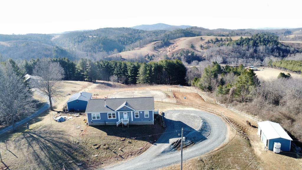 This beautiful 3-bedroom, 2-bath home built in 2024 sits on approximately 7 acres and offers outstanding long-range mountain and country views with privacy. The open living room features a cozy fireplace and flows into a well-appointed kitchen with stainless steel appliances and a center island. The large primary suite includes a walk-in closet and a soaking tub, double vanity, and walk-in shower. Two additional bedrooms provide comfortable space for family or guests. Hardwood and LVP flooring run throughout the home, complemented by a spacious mudroom with sink. Outside, enjoy peaceful country living with a 25x35 garage with electric and water, a 15x30 barn, fenced areas, and a riding ring. Ideally located near Little River and the New River, with convenient access to Sparta, NC and Galax, VA, this property offers a nice blend of modern comfort and rural charm. Call Today!
