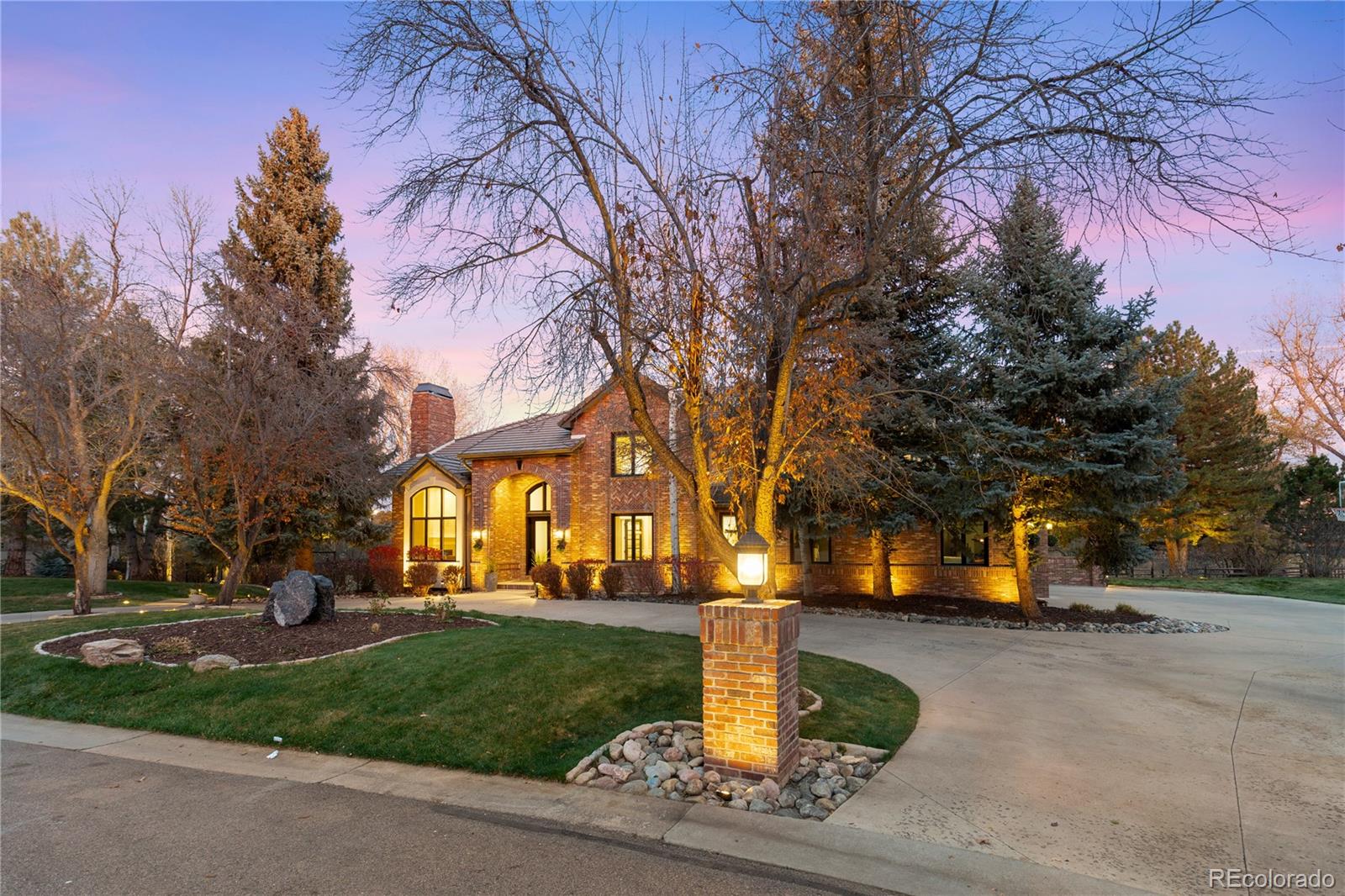 Tucked into mature trees, this brick estate pairs stately architecture with inviting warmth. Sunlight moves across grand, well-proportioned interiors finished with designer lighting, wrought iron railing, and finely crafted built-ins. The foyer makes a statement with a sweeping curved staircase. In the family room, coffered ceilings and a marble fireplace anchor everyday living. French doors open to a refined office. The formal dining room, framed by a tray ceiling, sets the scene for holidays. A butler’s pantry connects to an expansive kitchen with a cook’s island, casual dining, built-in desk, and top-of-the-line appliances. The kitchen opens to a full-length deck for relaxed meals and weekend entertaining. Practical spaces include a mudroom and a main-floor gym lined with windows.Upstairs, the serene primary suite is a true retreat with a fireplace, spa-like bath with freestanding tub and dual vanities, and a boutique-style walk-in closet. An additional ensuite bedroom and secondary bedrooms with walk-in closets complete the level. The lower level invites fun with an open recreation area, a cozy zone for movie nights, a convenient kitchenette, and a private guest suite. Walk out to the backyard where the setting lives like a resort, featuring a sparkling pool with waterfall features, broad patios for al fresco dining, and a level lawn for play. A three-car garage and easy guest parking complete the picture. Steps from the High Line Canal Trail and minutes from Cherry Creek and DTC, this exceptional home offers privacy, convenience, and resort style amenities in one of Greenwood Village’s most desirable neighborhoods.