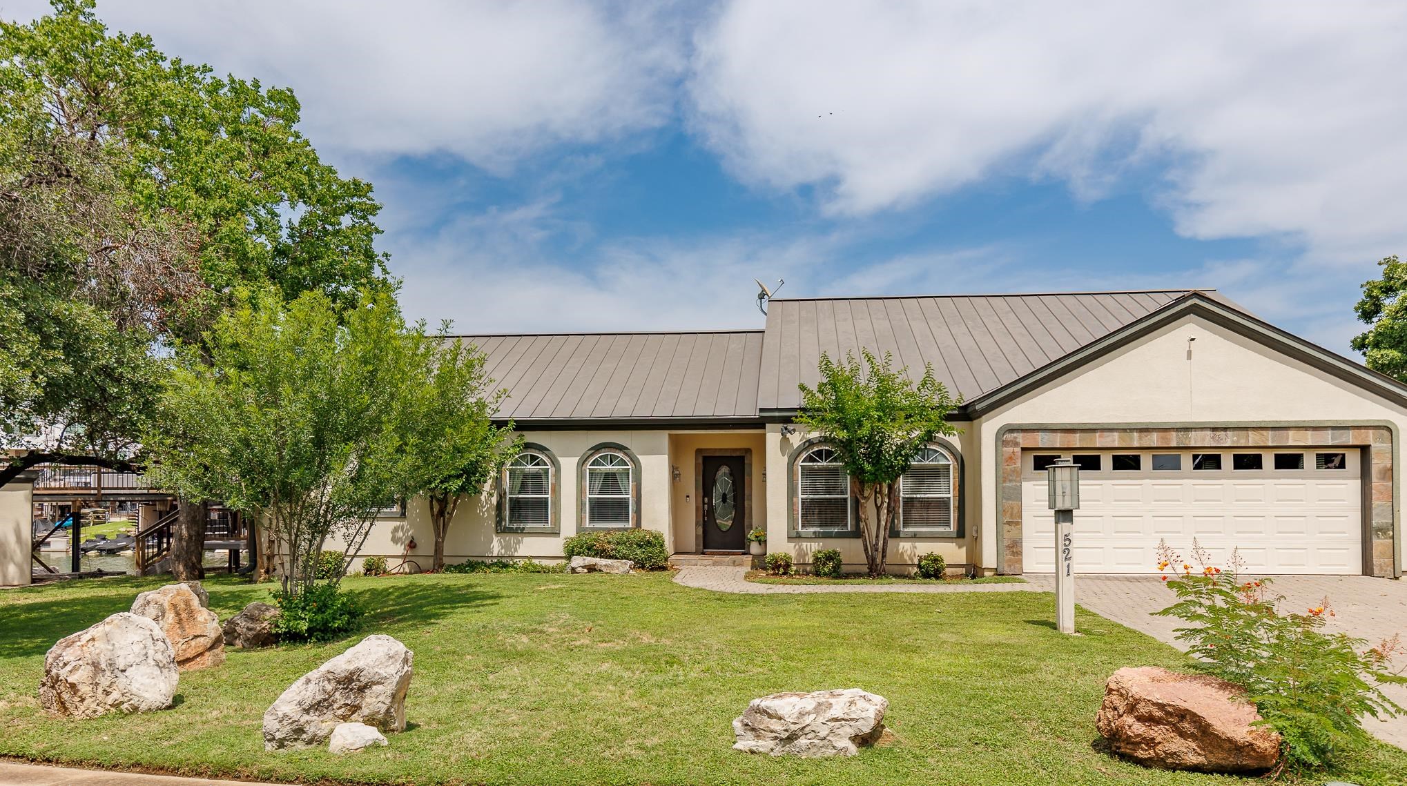 A rare expression of lakefront living on Lake LBJ, this true single-family residence offers 105 feet of private waterfront with no immediate neighbors on either side, just one house off open water.  Welcome to 521 Lucy Lane, a refined lakefront retreat where privacy, setting, and design come together along a quieter stretch of shoreline. Set apart from neighboring properties, the home offers a sense of space and calm, creating a more peaceful waterfront experience and a stronger connection to the surrounding landscape.  Oriented to the east, enjoy beautiful sunrise views from multiple outdoor living spaces designed for both relaxing and entertaining. A private dock and boat lift with direct canal access provide easy entry to open water while maintaining a more protected setting along the shoreline.  Inside, the light-filled open-concept design features soaring ceilings, expansive windows, and refined finishes throughout. The kitchen, complete with granite countertops and custom cabinetry, anchors the main living area and serves as a natural gathering space. HVAC replaced August 2024 adds comfort and peace of mind.  The layout offers flexibility for a full-time residence or lock-and-leave second home, with furnishings available upon request and subject to negotiated terms.  Located on a quiet cul-de-sac in Horseshoe Bay proper with full city utilities and no MUD tax. Short-term rentals are not permitted, preserving a peaceful residential setting.