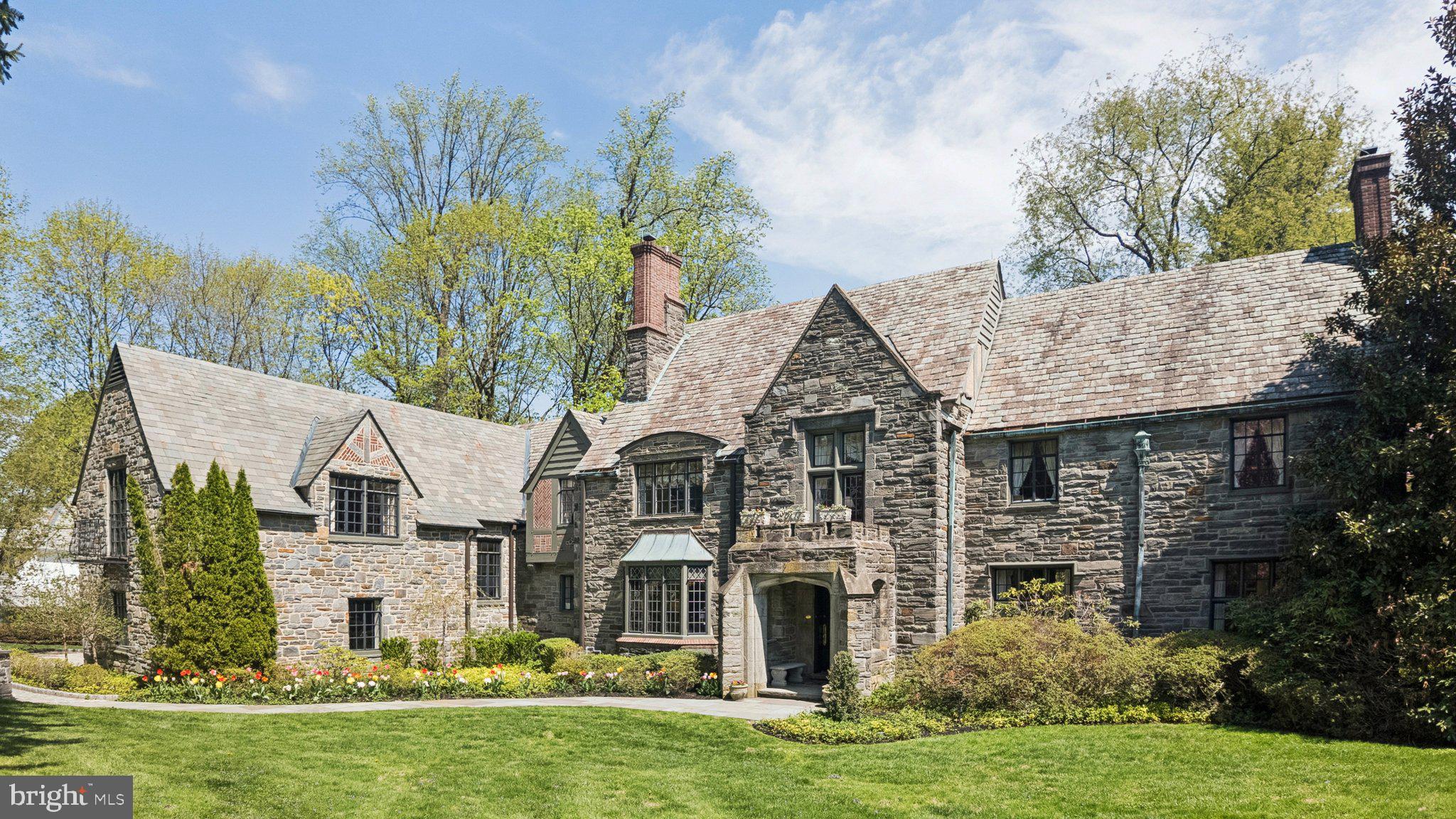Welcome to 517 Fishers Road — a masterfully preserved Tudor estate where timeless architecture meets refined modern living, set on a lush, private acre in the coveted Northside enclave of Bryn Mawr. From the moment you arrive, the home evokes the quiet grandeur of a bygone era, reimagined for today's most discerning buyer.The art of living begins in the gracious entry foyer, where rich hardwood floors set the tone for the elegance that unfolds throughout. A formal living room anchored by an ornamental fireplace invites intimate gatherings, while an adjacent sun-drenched reading room — lined with custom built-ins — offers a serene escape for quiet reflection.A richly paneled executive office, distinguished by stately stonework and an atmosphere of cultivated sophistication, serves as the ideal private retreat for those who work as beautifully as they live.As evening falls, the magnificent dining room becomes the undisputed centerpiece of the home — a stage for unforgettable entertaining, presided over by a glittering Baccarat chandelier that casts the room in pure glamour. Just beyond lies the true heart of the residence: a chef's kitchen that masterfully balances modern performance with timeless style. Outfitted with dual ovens, a custom-paneled refrigerator, Miele induction cooktops, and bespoke butcher block counters, this is a space where everyday moments feel like occasions. The kitchen flows effortlessly into a sun-drenched sunken living room with soaring coffered ceilings and a breathtaking Delft-tiled fireplace — a wall of windows framing the private stone patio beyond. Two elegantly appointed powder rooms complete the main level's seamless design for elevated entertaining.The upper levels are home to five spacious and luminous bedroom suites, each a bright and private sanctuary. The primary suite is a world apart — a true retreat featuring a spa-inspired ensuite with a deep soaking tub, a beautifully tiled walk-in shower, and a generous walk-in closet. A half-flight above, an additional bedroom and a versatile bonus room with vaulted, beamed ceilings offer an elevated sense of seclusion and possibility.Above it all, the attic level presents a remarkable opportunity: a fully realized fitness studio alongside generous storage and a cedar-lined closet — a rare and welcome luxury.Descending to the lower level, a wood-paneled billiards room evokes the atmosphere of a distinguished private club, complete with a temperature-controlled wine cellar — the perfect setting for an after-dinner scotch or an evening among close friends.Outside, the estate's grounds are nothing short of spectacular. Framed by mature, manicured landscaping and serene natural vistas, the one-acre setting feels both expansive and intimate. Dual stone patios create idyllic spaces for al fresco dining and unhurried relaxation, while a tranquil water feature lends a sense of peaceful seclusion rarely found so close to the vibrancy of the Main Line.Completing the offering: a whole-home generator and a sophisticated security system ensure that life here is as effortless as it is extraordinary.Situated within the top-ranked Lower Merion School District and moments from elite private schools, world-class dining, and the cultural riches of Center City Philadelphia, 517 Fishers Road is that rarest of offerings — a home of historic soul and contemporary grace, in a setting that simply cannot be replicated.