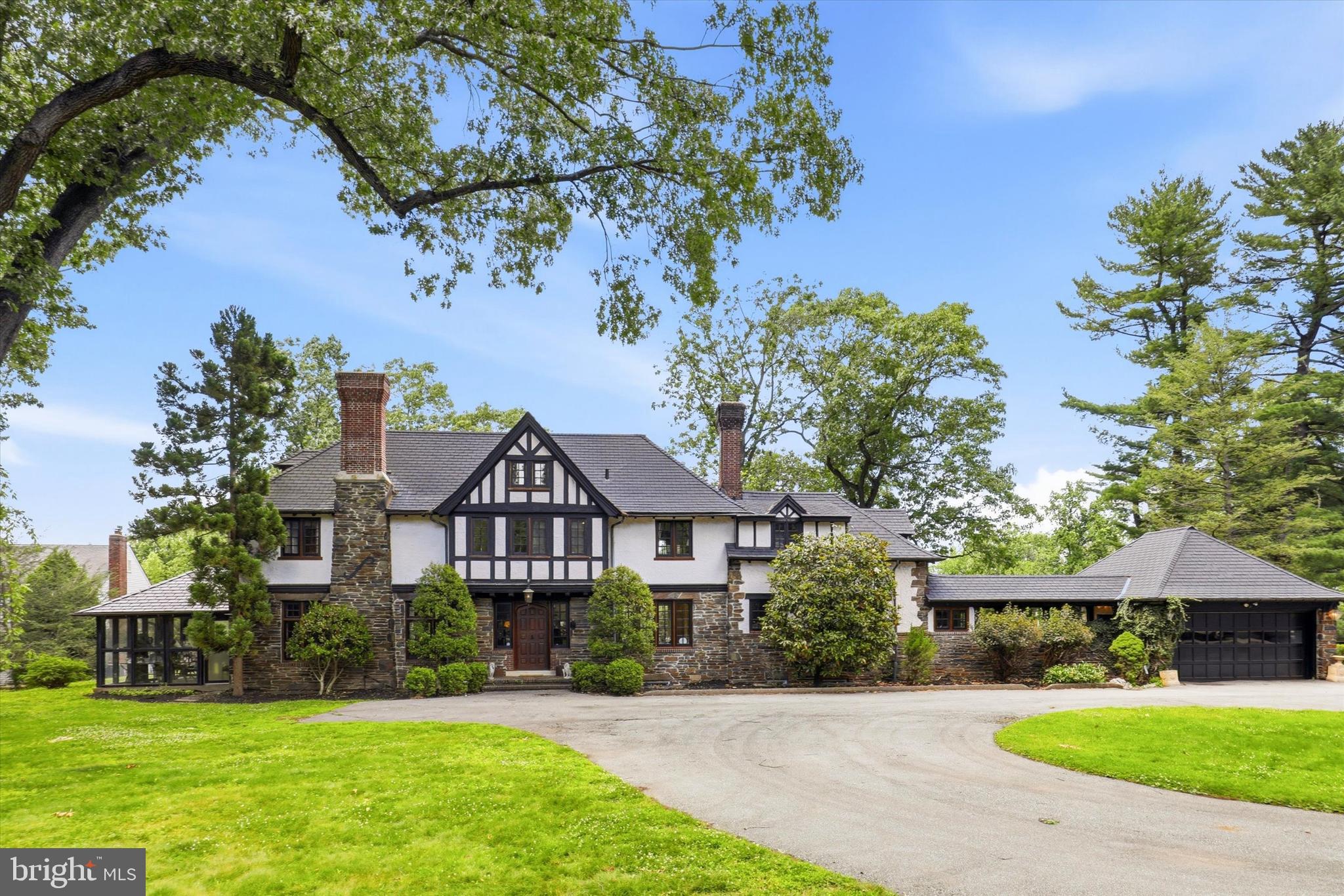 This stunning historic Tudor-style and traditional home located at 422 Donalyn Lane in Berwyn, Pennsylvania, offers 5 bedrooms and 3 full beautifully appointed bathrooms and two powder rooms in a meticulously maintained residence that captures the elegance of classic architecture. The home showcases exceptional ornate woodwork throughout, including custom crown moldings, detailed wainscoting, and decorative trim that highlights the craftsmanship of the era. A welcoming fireplace serves as the focal point of the main living space, creating a warm and inviting atmosphere for gatherings throughout the year. The heated sunroom provides a bright, energy-efficient extension of the living area, perfect for enjoying natural light regardless of the season, while the finished attic adds versatile additional space ideal for an office, guest room, or recreational area. The marble bathrooms feature refined fixtures and timeless design elements that elevate the home's overall luxury. Below, a sophisticated wine cellar offers dedicated wine storage. The beautifully landscaped exterior complements the distinctive Tudor-inspired architecture with its steeply pitched gables, decorative half-timbering, and stately brick façade, creating a visually striking presence on the street. This well-preserved property represents an excellent opportunity for buyers seeking the character and charm of a historic home with modern functionality in the desirable Berwyn community within the highly rated Tredyffrin-Easttown School District.