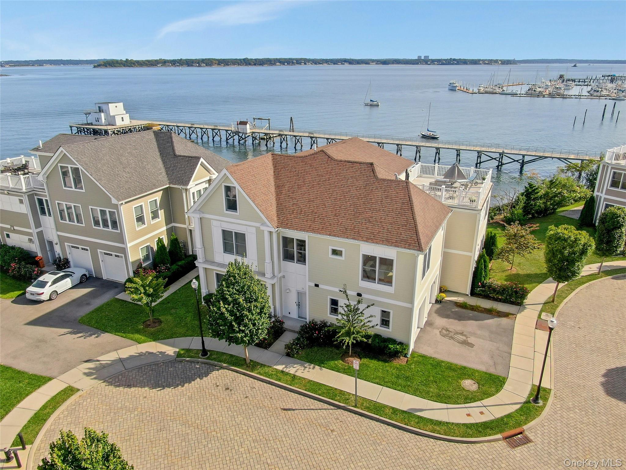 This luxury waterfront home on the Long Island Sound epitomizes elegance and sophistication, offering unparrelled views and a unique living experience. Expansive terraces enhance the residence, perfectly capturing the serene beauty of the water. The spacious 33-foot living room is designed for relaxation and entertainment, featuring a gas fireplace, custom built-ins, and three floor-to-ceiling French doors leading out to a terrace ideal for sipping coffee while watching the sunrise on the LI Sound.  The gourmet kitchen is a culinary haven, equipped with GE Profile stainless steel appliances, white maple wood cabinets, and Caesarstone countertops. A dining area adjacent to the kitchen offers breathtaking water views, creating a delightful setting for meals. The primary suite serves as a luxurious retreat with access to the terrace, custom closets, and an en-suite bath adorned with Carrera marble accents.  In addition, the home includes a large second bedroom with an en-suite marble bath and ample closet space. The upper level boasts a generous living area complete with a wet bar and access to a 500 square foot terrace, ideal for entertaining guests. This level also features a versatile third bedroom or large office space with a custom walk-in closet, a full bath, and extensive storage options.  Throughout the home, attention to detail is apparent, with features such as beautiful hardwood floors, Andersen windows and doors, and high ceilings that blend style with comfort. Additional conveniences include spacious walk-in closets, a one-car attached garage, and central air conditioning for year-round comfort. Located within a private gated community, residents enjoy resort-style amenities including a clubhouse with a fitness center and a heated in-ground swimming pool. Resort-style living at its finest!