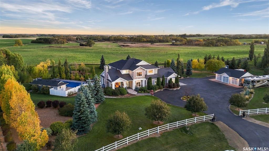 Immaculate inside and out. This Casa Rio estate sits on 2.49 gently rolling acres backing open field, with an unobstructed south-facing view and Saskatoon only minutes away. Since 2024 the owners have invested more than $247,000 in the property, and it shows from the moment you pull onto the freshly paved and sealed driveway.The 3,892 sq ft two-storey walkout offers five bedrooms and four bathrooms. A grand entry with a statement chandelier opens to bright living spaces with new LED lighting and motorized blinds. The gourmet kitchen has a new 48-inch refrigerator and 36-inch gas range, expansive prep space and high-end cabinetry, with a breakfast nook, formal dining room and main-floor office close by. A new gas fireplace with mantle and stonework anchors the sitting room. Upstairs, the primary suite has a five-piece ensuite with in-floor heat, and a new laundry room with built-in cabinetry and quartz counters sits right where you need it.The walkout lower level is made for entertaining: theatre room, humidity-controlled wine room, wet bar, exercise room and new carpet, all with in-floor heat.Outside, it lives like a resort. A saltwater pool with electric cover, heated pool house with bathroom and outdoor shower, six-person hot tub and concrete sport court are framed by new landscaping, a rock garden and automatic sprinklers on a separate irrigation well. Two GPS robot mowers and permanent celebration lighting are included.There is room for every vehicle: an oversized triple attached garage with in-floor heat, a heated triple detached garage, and new RV and trailer parking with two RV plugs. Two new air conditioners, city water to the house, a Control4 smart home system and a new camera and security system round out the list.Around the corner from South Corman Park School. Nothing left to do but move in.