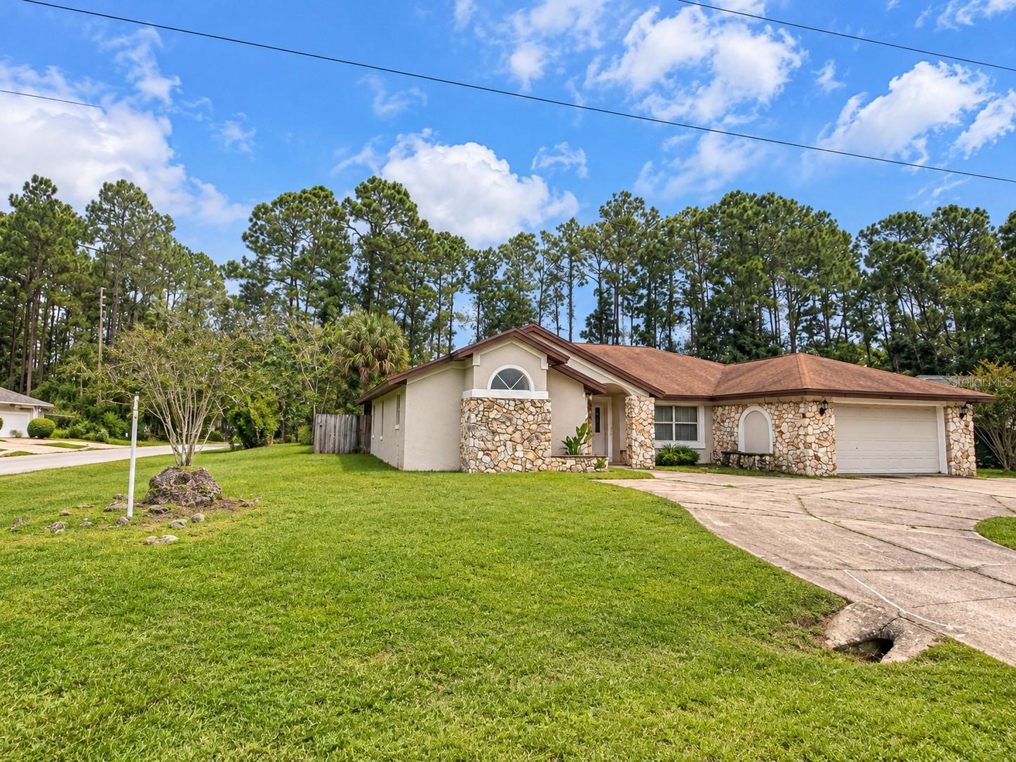 POOL HOME WITH CHARACTER, SPACE & ENDLESS POTENTIAL! Welcome to 1 Windsor Place in Palm Coast! This distinctive home offers an inviting layout with plenty of room to make it your own. Step inside to discover spacious living areas, attractive wood-look flooring, vaulted ceilings with skylights, and abundant natural light. The kitchen features wood cabinetry, generous counter space, a breakfast bar, and views of the screened pool area. A beautiful stone fireplace adds character, while the primary bathroom features dual vanities, a soaking tub, and a separate shower. Sliding glass doors lead to the screened pool and outdoor entertaining area, complemented by a fenced backyard with mature trees and room to enjoy the Florida lifestyle. With its unique architectural features and opportunity for personalized updates, this home offers tremendous potential. Bring your vision and make this Palm Coast property your own!