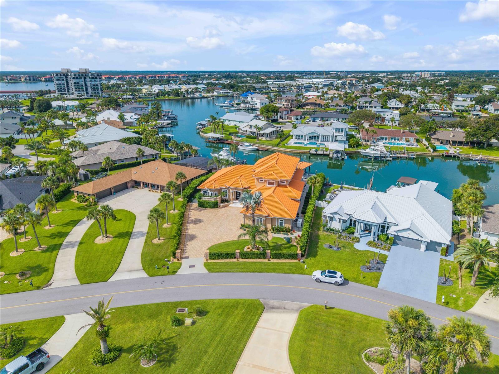 Introducing one of New Smyrna Beach's finest turnkey waterfront estates. Masterfully reimagined by the acclaimed design team at Saxon-Clark Furniture & Design of Altamonte Springs, this extraordinary residence represents a rare fusion of timeless architecture, bespoke craftsmanship, and modern coastal luxury. Offering over 5,600 sqft under air and more than 7k square feet under roof within the prestigious waterfront community of Venezia, every detail has been thoughtfully curated to create a home of exceptional beauty and enduring quality. Designed for those who appreciate exceptional architecture and effortless luxury, this five-bedroom, five-and-a-half-bath estate perfectly balances grand entertaining with comfortable everyday living. The thoughtfully designed main level features an executive office, formal living and dining rooms, and an expansive entertaining room that flows seamlessly into the designer kitchen and outdoor living spaces. Three private bedroom suites, including the luxurious primary wing with dual walk-in closets and an extraordinary spa-inspired bath, are located on the first floor. Upstairs, two oversized guest suites with private en-suite baths, a convenient kitchenette, and an expansive waterfront balcony provide the perfect retreat for family and guests. Designed for both everyday living and entertaining, the chef's kitchen showcases GE Monogram appliances, striking granite countertops, custom cabinetry, an oversized center island, and a hidden walk-in pantry. A beautifully appointed entertaining bar featuring dual wine coolers and a built-in beverage refrigerator completes the space. The private primary suite is a true sanctuary, highlighted by heirloom wire-brushed oak flooring and an extraordinary spa-inspired bath appointed with Calacatta honed and polished marble, custom Calacatta marble mosaics, illuminated quartzite and onyx feature walls and countertops, a 72inch Kallista soaking tub, a Steamist steam shower, and TOTO's renowned luxury bath collection, creating a true five-star retreat. Luxury extends well beyond the living spaces with a dedicated climate-controlled fitness room, climate-controlled garage, three high-efficiency HVAC systems with integrated dehumidifiers, premium travertine flooring, John-Richard designer lighting, motorized interior blinds, and MagnaTrack progressive hurricane screens protecting the rear lanai and upper terrace. Beyond the walls of glass, the estate unfolds into an extraordinary private waterfront retreat. Marble pool decking surrounds the resort-style pool and elegant spillover spa, while premium artificial turf, a brand-new seawall, and a new composite dock equipped with two boat lifts, including an impressive 27k lb lift, complete this exceptional outdoor living experience. With direct Intracoastal access and no bridges to Ponce Inlet, this property offers effortless access to the Atlantic Ocean, world-class fishing, and endless days on the water. Additional premium features include an updated tile roof, whole-house Generac generator, and countless custom finishes reflecting an unwavering commitment to craftsmanship and quality. Rarely does a residence of this caliber become available. Offered as one of New Smyrna Beach's most distinguished waterfront residences, this remarkable estate showcases inspired design, exceptional craftsmanship, and unparalleled boating access—an extraordinary opportunity to own one of New Smyrna Beach's most iconic waterfront estates.