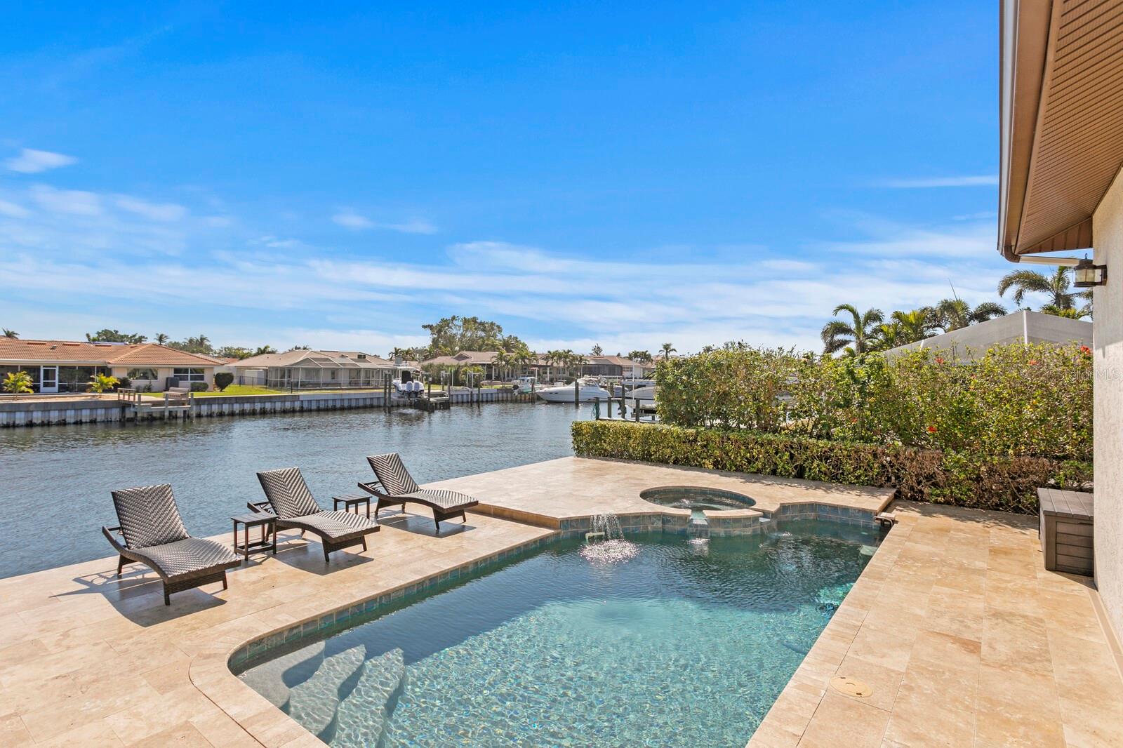 Nestled in the prestigious Venetian Isles, this Modern Mediterranean home offers 90 feet of deep-water frontage with direct access to Tampa Bay, delivering the best in single-level living. Custom-built in 2007 and ideally positioned on the east side of the street, this home boasts a thoughtfully designed layout, where three of the four bedrooms feature en-suite baths. The open-concept design is perfect for both everyday living and entertaining, featuring a formal dining area, an eat-in kitchen, and a spacious island with ample seating. A Wolf gas range and a stylish coffee bar complete the gourmet kitchen. The primary suite serves as a private retreat, offering a separate seating area with serene views of the pool and water. The luxurious primary bath includes dual vanities, a sit-down dressing area, and a charming clawfoot tub, while the expansive walk-in closet is thoughtfully organized and even includes a second laundry area. A dedicated office with built-ins and water views enhances the home’s functionality. Elegant details such as 10-foot ceilings, crown moldings, plantation shutters, and travertine flooring throughout create an inviting ambiance, seamlessly leading to your dream waterfront oasis. Enjoy alfresco dining in the screened-in outdoor kitchen, equipped with a DCS stainless grill and Viking smoker, while overlooking your private dock with triple boat lifts. The travertine-surrounded saltwater pool and spa provide the perfect vantage point to observe manatees, dolphins, and coastal birds, all while soaking in Florida’s endless sunshine. A grand three-tier fountain welcomes you at the circular driveway, offering ample off-street parking alongside a spacious two-car garage with additional storage. This is truly a must-see waterfront retreat!