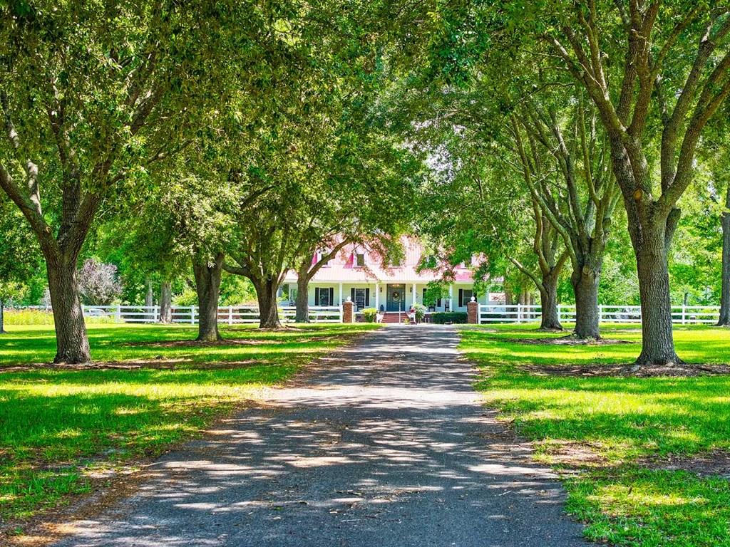 Gorgeous custom built home on nearly 57 acres in South Georgia with a pond! Welcome to CheraOak Plantation, a place where quiet mornings, wide-open views, and time spent with family take center stage. Nestled on nearly 57 acres  just down the road from Burton Brooks Farms (and delicious peach ice cream, this gated estate offers the privacy and peacefulness of country living without sacrificing comfort or character. Conveniently located in Brooks County within minutes from Quitman, and within an easy reach of Thomasville, Hahira, Moultrie, and Valdosta. Brooks County is widely recognized for agriculture heritage, abundant wildlife, and plantation landscape. Thoughtfully designed and filled with warmth, the approximately 4,500-square-foot home features 4 bedrooms, 3 full bathrooms, and 2 half bathrooms. Inside, you'll find two inviting fireplaces, generous gathering spaces, and a dedicated office complete with custom built-in bookshelves—perfect for working from home or enjoying a quiet place to read and reflect.  One of the home's most cherished features is its expansive wraparound porch, offering the perfect place to enjoy a cup of coffee, watch wildlife, or take in the beautiful views of the surrounding property. Established flower gardens, mature landscaping, and a pond create a setting that feels both peaceful and picturesque year-round.  With nearly 57 acres stretching almost a mile from front to back, this remarkable tract offers a level of privacy that is increasingly hard to find. The depth of the property provides excellent opportunities for hunting, wildlife observation, trail riding, and outdoor recreation while still maintaining the beauty and serenity of a true country estate.  Additional highlights include a basement-level two-car garage, abundant storage, and acreage well-suited for recreation, gardening, horses, or simply enjoying the outdoors. Outbuildings include a shop, man cave, and a fabulous playhouse. Whether envisioned as a private retreat, sporting estate, or a family legacy property, CheraOak offers a rare opportunity to own a piece of South Georgia's landscape.