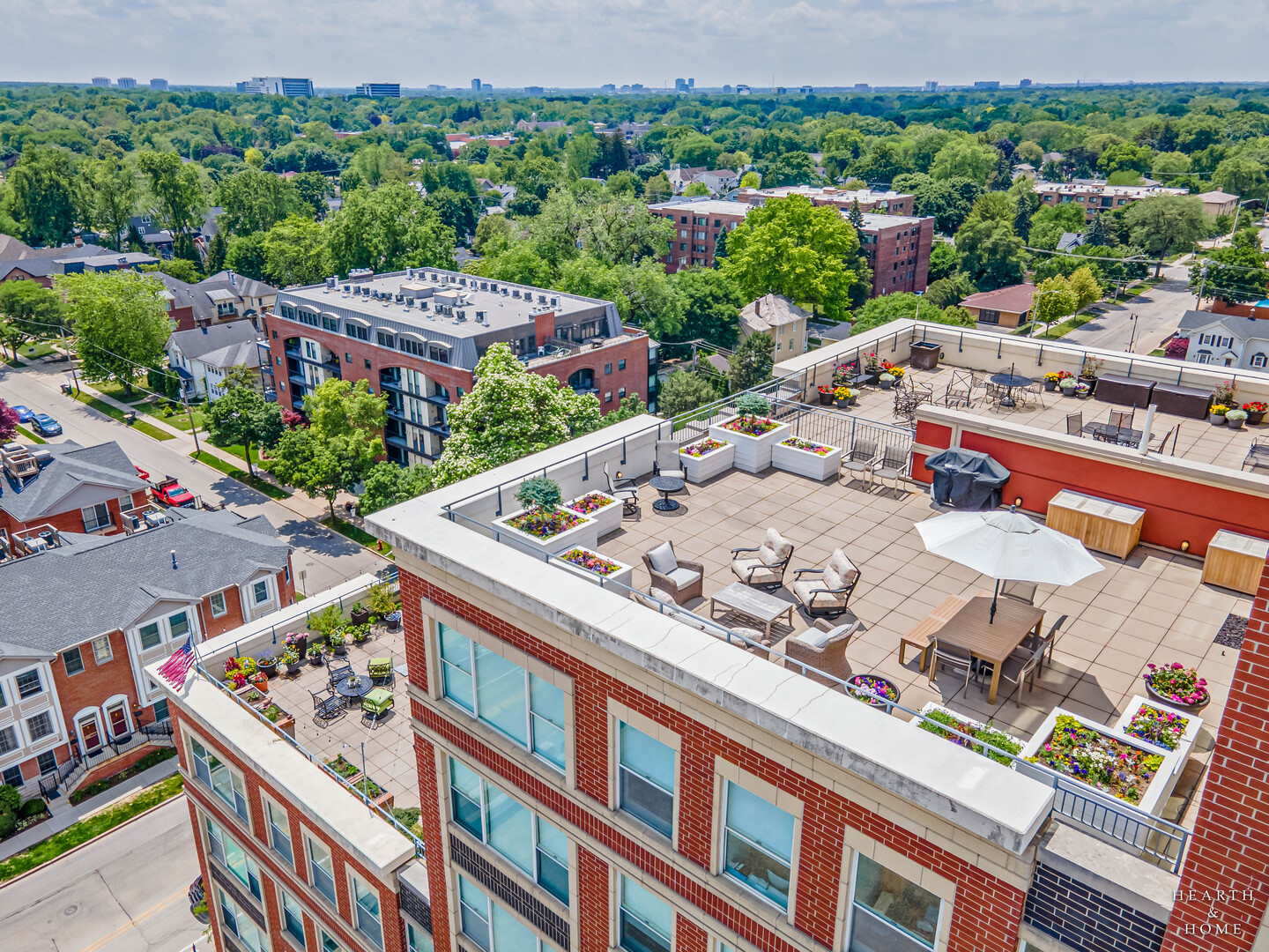 Welcome to Luxurious & Sophisticated 77 S Evergreen Avenue #1103 in the Heart of Downton Arlington Heights! This Prestigious Corner Unit is one of only 6 units that has a magnificent 1200 square foot Private Patio that takes in Breathtaking Panoramic Views including the Chicago Skyline and what could be the new Bears Stadium! Imagine all of the luxuries of condo living without having to give up your outside living space! Your pets will love it too! The home features a beautiful foyer that leads you right into the gorgeous kitchen that was just remodeled in 2024! It features stunning Quartz Counter tops, a New Wolf Induction Cooktop, stunning cabinetry, Top Tier appliances, a generously sized Island with room for stools, a dramatic built in with illuminated cabinetry and a desk!  All this and a perfect view of the Arlington Clock Tower from every room in the home!  The Grand Great Room features wall-to-wall windows, Brazilian Koa Hardwood floors throughout, high end custom built in cabinetry including a wine fridge.  The Main suite boasts dual walk-in closets and a private ensuite with both a shower and jetted tub.  It also has its own private balcony!  Ideal for quiet afternoons reading your favorite book. The second bedroom is perfect for family, guests, or a home office. There are 2 deeded, highly desirable, parking spaces that are easily pulled straight into.  They do not have vehicles on either side of them. There is direct access from the garage to the condominium floors, as well as secure access to the shopping area, no daily parking hassle. The 2nd floor provides a wonderful exercise facility, as well as a versatile recreation room, and a Private Storage Unit can be found here too for your convenience. You are minutes to everything downtown Arlington Heights has to offer, walking distance to Metra, as well as easy access to highways, expressways, Ohare Airport and Woodfield Mall.  Steps away from Dining at Arlington Alfresco! Everything in this home has been crafted and cared for at the highest level. We were under contract in ONE DAY- buyers had a change in circumstances, giving you a 2nd chance at this magnificent home!