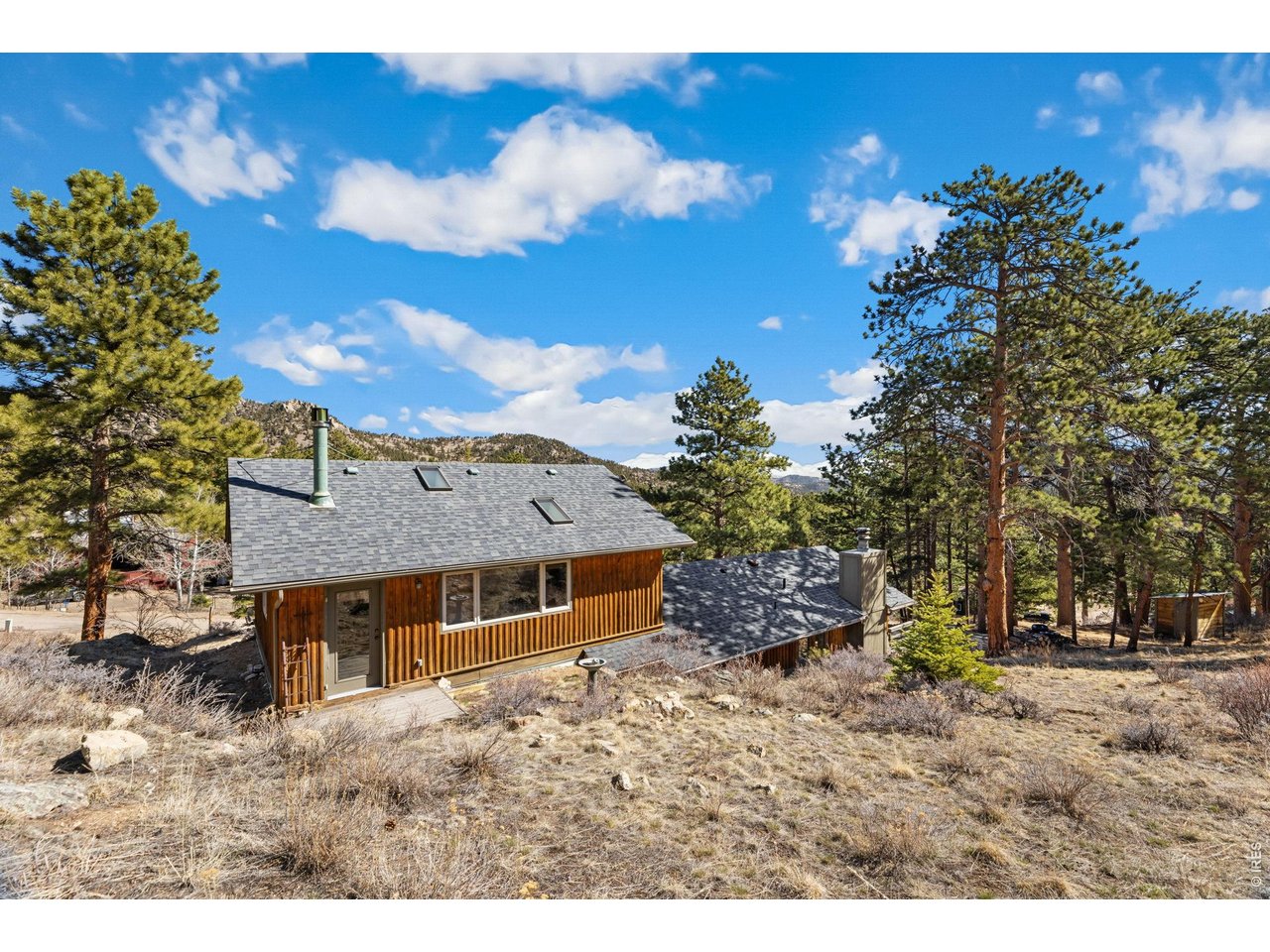 A Hikers Paradise! Walk to RMNP views in minutes! Whether you're seeking a peaceful full-time residence or vacation home, this property offers a rare sense of respite from everyday life. Quiet, private, and deeply connected to nature, this 2 bedroom, 2 bath, end-of-the-road mountain retreat rests on .56 acres just steps from Rocky Mountain National Park, allowing you to access miles of hiking trails while avoiding the park's timed entry system. Originally built in 1928 and thoughtfully remodeled, this cabin home blends authentic mountain character with modern comfort. Details of a wood-burning fireplace, heated tile floor, and seamless access to the deck and flagstone patio create inviting spaces that encourage you to slow down and soak in the surroundings. Upstairs, a separate living area with vaulted ceilings, skylights, and a cozy wood stove provides the perfect retreat for visiting family and friends, offering privacy while remaining connected. Complete with a heated two-car garage and surrounded by towering pines, this is your home to recharge, reconnect with nature, and create lasting memories in one of Estes Park's most coveted settings.