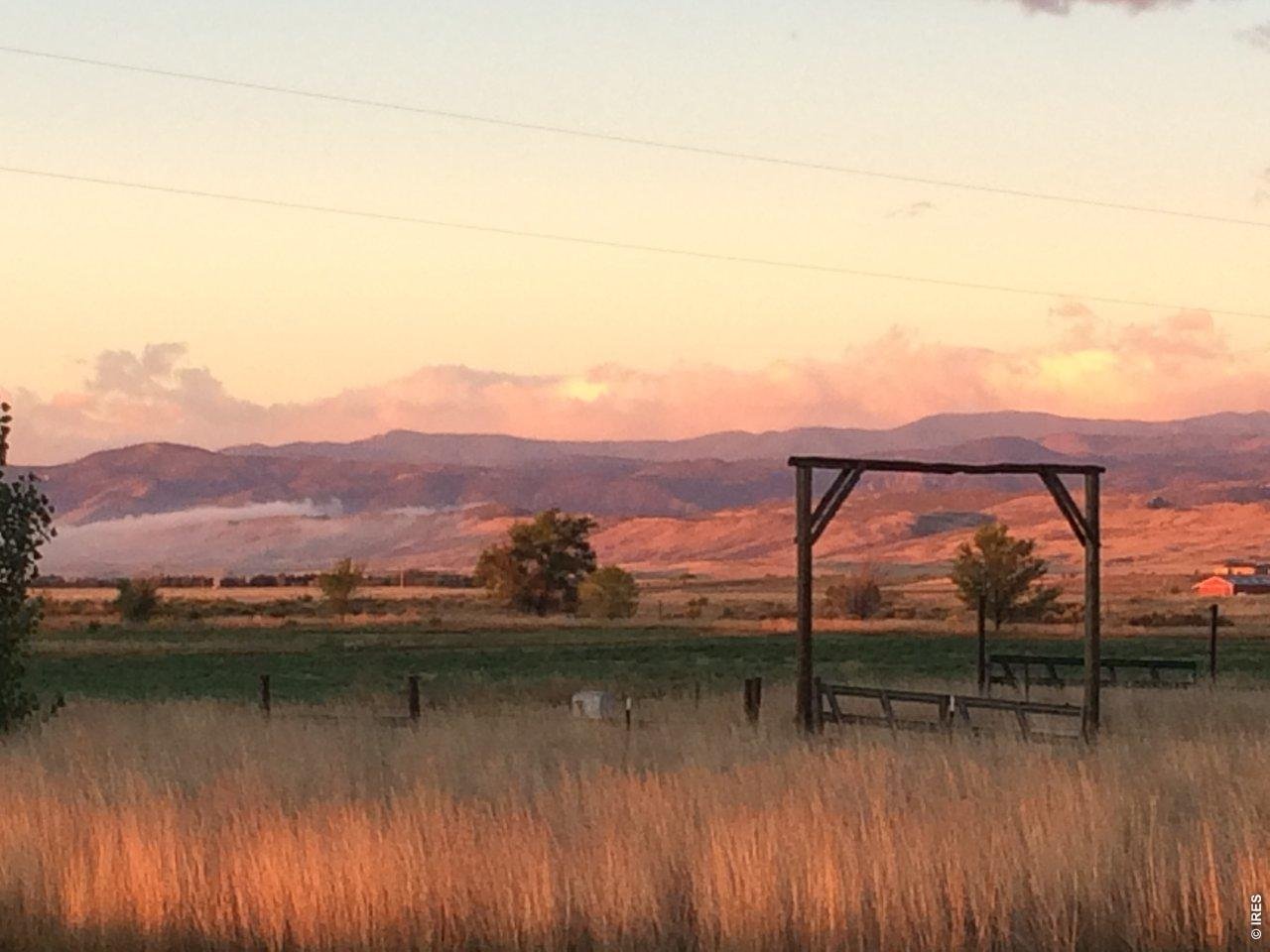 Imagine sitting on your front porch for a relaxing sunset and a view of the Front Range - set in open landscapes of northern Larimer County, 620 W County Road 74 offers a blend of rural privacy, panoramic views stretching across the plains toward the Front Range and surrounding foothills, and comfortable living in an over 2800 sq ft stick-built home. The residence is thoughtfully arranged with a main-level layout that encourages easy circulation between gathering spaces, creating an environment equally suited for everyday living and welcoming guests. Natural light filters through the home, complementing open living areas that connect naturally with the kitchen and dining spaces. You'll love the custom hickory cabinets, hickory and slate floors, remodeled bathrooms, and wood burning stove. This practical design supports both daily routines and larger gatherings. The primary suite offers a private retreat and adjoins the expansive patio, while additional bedrooms provide flexibility for guests, workspace, or changing household needs. Supporting spaces include a flagstone patio and pergola, oversized garage, three-sided structure with attached garage / workshop, full barn with electric, automatic waters, and hay storage for all of your animals. The property's expansive grounds present opportunities for a wide variety of rural pursuits, with established fencing, pasture areas and corrals. The surrounding landscape offers a quiet setting where wide-open skies, mountain views, and the rhythm of country living become part of everyday life. Outdoor enthusiasts will appreciate the proximity to Soapstone and Red Mountain Open Space, lakes and trails. This property presents an appealing opportunity for buyers who value privacy, flexibility, and a rural lifestyle without sacrificing connection to the conveniences of Wellington and Fort Collins.
