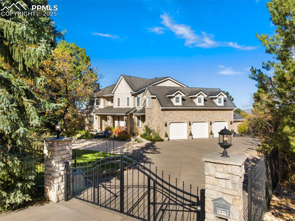 A golfers dream, this extraordinary custom residence backs to and overlooks the Broadmoor Golf course with the stately hotel and lake in the background. A short walk on a private path takes you to Broadmoor West.  Offering over 8,000 sq ft of refined living designed for luxurious entertaining and everyday comfort. Set on more than an acre of beautifully landscaped grounds, the home is accessed through its own private gated entrance for exceptional privacy. A grand foyer is flanked by French-door access to formal living room on one side and an elegant dining room on the other. Beyond the foyer, the home unfolds into an inviting open-concept great room thoughtfully arranged to maximize breathtaking golf course and Broadmoor resort views. Here, the gourmet kitchen, dining area, and family room with wood burning fireplace seamlessly connect to create an ideal setting for relaxation and entertaining. The chef’s kitchen features slab granite counters, custom cabinetry, Sub-Zero refrigerator, double Thermador ovens, gas range, and dual dishwashers. The family room with beamed ceilings and wet bar opens to an expansive deck with hot tub plus views of the city to Garden of the Gods. Rich details include custom millwork, crown molding, four gas fireplaces, and large windows and doors that flood the home with natural light. A main-level study with built-in bookcases offers the perfect work-from-home retreat. Upstairs, the luxurious primary suite boasts a fireplace, exceptional views and spa like bathroom. Three additional bedrooms and a spacious flex room complete this level. The walkout lower level has a large recreation area, fitness room, 2 large bedrooms, full bath and abundant storage. Extras are a generous laundry room, 3 furnaces, 4 fireplaces, built-in speakers, steam shower, and newer deck. Quietly elegant yet undeniably grand, this rare property combines privacy, breathtaking views, and easy access to an iconic Colorado destination. Your Broadmoor dream home awaits.