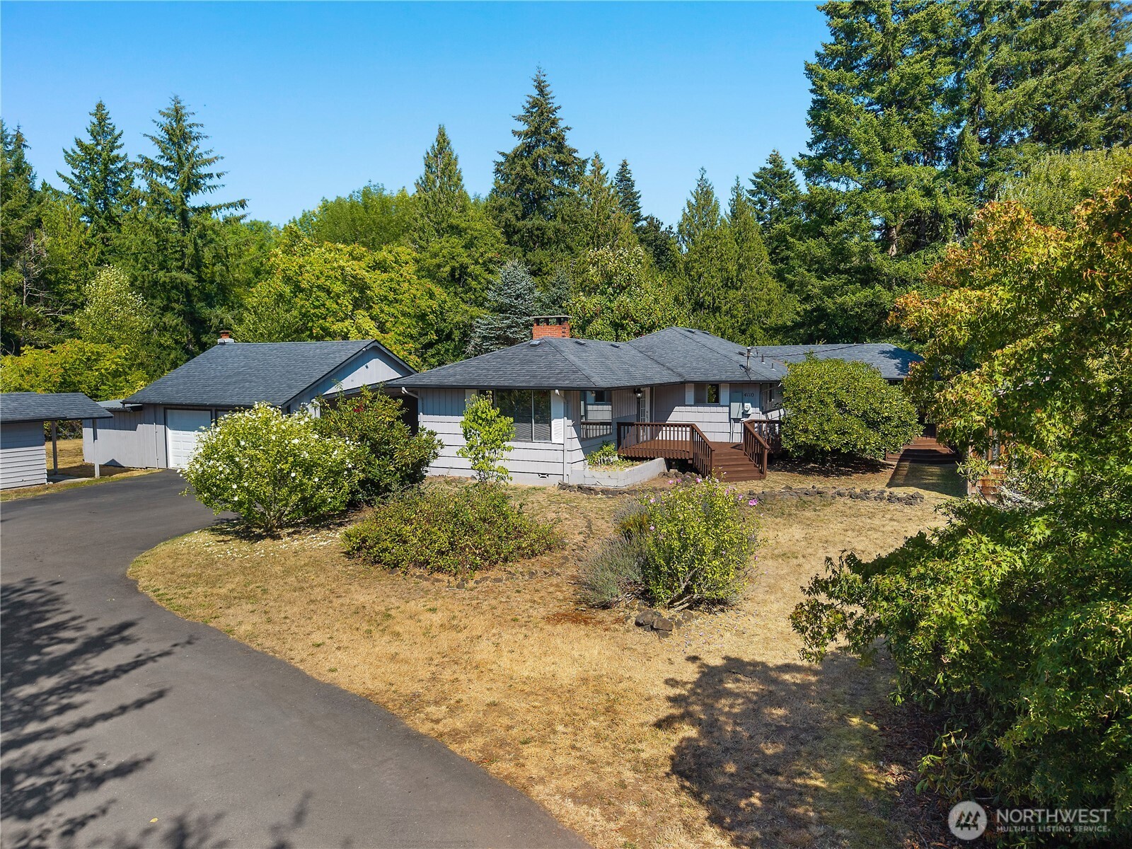 Room to spread out, gather, and grow on a fully fenced acre! This 3,096 sq ft home offers 4 bedrooms, 2.5 baths, a 5-bedroom septic, and tons of flexible living space, including a huge downstairs ideal for multigenerational living. The primary bedroom features a large walk-in closet and private covered deck access. Fresh interior paint, high-quality non-slip deck coating, A/C, wood-burning stove, and an approx. 8-year-old roof. Outside, enjoy a beautiful wraparound deck, apple orchard, several plum trees, giant established grapevine, lavender, and a large garden area once used as a multigenerational family garden. There’s plenty of room for vehicles, projects, and storage with a two-car garage, workshop area, wood storage, and large covered carport.
