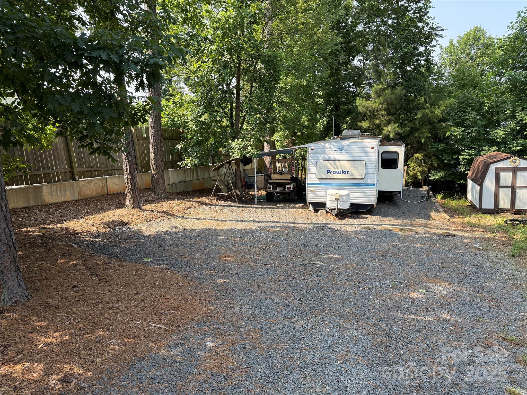 Starter unit here in the park. This 1996 Prowler is 31', with queen in primary and 2 twins in the bunk nook. Most furnishings to remain. New refrigerator last year. Private location within the park. This is an interesting lot.  Common area was purchased and this lot goes from Powder Horn to Lake Tillery Tr. Current owner has the concrete catch basin box if you are interested in making this a drive through lot. Included at no charge, you have to pick up. Come and see if this is your "Happy Place" here in the park. All clients must be with a realtor to gain access to the community.