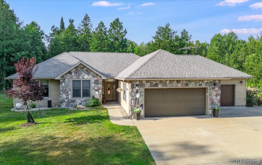 Tucked away in a secluded woodland paradise with a winding private driveway, this spacious ~2443 Sq Ft custom ranch offers a serene escape on a vast, mostly wooded lot with a tranquil pond view, blending privacy and wildlife with the convenience of being just a short drive from a major grocery store, the expressway, downtown, premier golf courses, and abundant outdoor activities. Step inside to an inviting open-concept layout, where a welcoming foyer flows into a generous living room with a large four-panel door wall showcasing an expansive stamped concrete patio and lush backyard. The home’s custom oak cabinetry, woodwork, and solid oak interior doors exude timeless elegance, complemented by sleek Corian countertops, tile, and hardwood flooring. The well-appointed galley kitchen, a chef’s delight, ample storage with multiple pantry cabinets, numerous drawers, and wall & base cabinets, seamlessly connecting to a sizable family room with oversized windows, a bar area, and French doors opening to the patio. The primary suite is a roomy retreat, featuring a walk-through closet with dual dressers and organizers, leading to a luxurious bath with a spacious dual shower, dual sinks, and abundant storage. Additional bedrooms offer built-in countertops, large closets, and large windows, while a full second bathroom ensures comfort. Radiant in-floor heating throughout delivers a warm, allergen-reduced embrace, enhancing the home’s well-insulated, tranquil ambiance.  Outside, a blacktop and gravel circle driveway reduces summer heat, paired with an attached multi-car garage with radiant heat and built-in shelving, and a detached expansive pole barn with a heated workshop, office, and versatile kennel area. With ample parking, a newer hip roof, and a convenient laundry room off the kitchen, this home offers unmatched storage, craftsmanship, and serenity, perfect for those craving a private retreat with modern conveniences and nature at their doorstep. Agent related to owner.