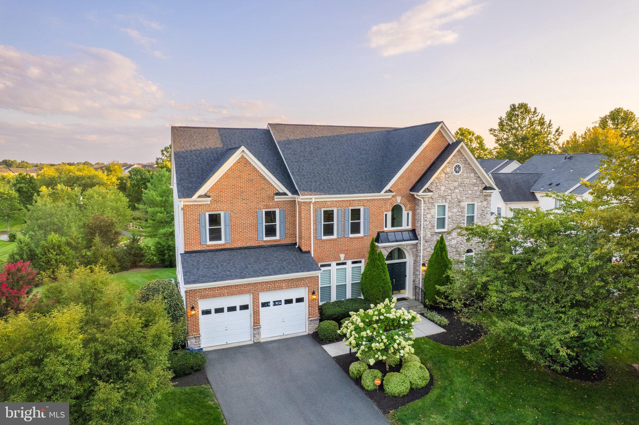 Tucked at the end of a cul-de-sac and backing to mature trees in sought-after Stone Ridge, this beautifully renovated brick-front Colonial offers more than 5,300 finished square feet across three levels, four bedrooms, four-and-a-half baths, and  $300,000 in renovations and improvements. Gracious living spaces, beautifully updated interiors, and a floor plan designed for both gathering and everyday life create a home that feels as welcoming as it is impressive.Step inside the grand two-story foyer, where a redesigned sweeping staircase makes an elegant first impression and open sightlines extend to the soaring two-story family room beyond. Formal living and dining rooms flank the foyer, while a private home office features custom built-in cabinetry and shelving.At the heart of the home, the soaring two-story family room is anchored by a dramatic floor-to-ceiling stone gas fireplace. Completely reimagined in 2020, the adjacent kitchen was designed with both everyday living and entertaining in mind, featuring abundant cabinetry, an expansive center island with generous seating and prep space, quartz countertops, wine refrigeration, and premium Thermador appliances including refrigerator/freezer, gas range with double ovens, and two dishwashers. A butler's pantry connects the kitchen to the formal dining room, while the kitchen, family room, and deck flow seamlessly together, creating an inviting space for everything from quiet evenings at home to gatherings with family and friends. A renovated mudroom, drop zone, and laundry room connect the kitchen to the garage, while new 10-inch wide-plank hardwood flooring extends throughout the main level and upper hallway.Upstairs, an open landing overlooks both the foyer and family room. The spacious primary suite offers separate sleeping and sitting areas, two walk-in closets, and an en suite bath with dual vanities, soaking tub, separate shower, and private water closet. A junior suite enjoys a private full bath, while two additional bedrooms share a Jack-and-Jill bath.The finished lower level offers an expansive recreation and game room with wet bar, a full bath, dedicated storage and utility rooms, and walk-up access to the tree-lined backyard.The extra-deep, extra-tall two-car garage provides abundant space for vehicles, storage, hobbies, or a workshop, with the potential to accommodate car lifts and expand capacity to as many as four vehicles.Significant updates include custom office built-in cabinetry, a redesigned front staircase, and new deck stairs completed in 2016. In 2020, the kitchen, family room, mudroom, and drop zone were extensively renovated, along with the addition of new 10-inch hardwood flooring and trim. A new roof, windows, and HVAC system followed in 2021. The property also features an irrigation system.Stone Ridge residents enjoy multiple pools, basketball courts, sports fields, tot lots, and a clubhouse with fitness center, along with nearby 26-acre Byrne Ridge Park. Gum Spring Library is within walking distance, while Dulles South Recreation & Community Center, shopping, dining, and everyday conveniences are minutes away. Nearby Stone Ridge Park & Ride and easy access to Routes 50 and 28, the Dulles Greenway, and Dulles International Airport make commuting throughout Northern Virginia and beyond convenient.With its gracious living spaces, thoughtful renovations, and peaceful setting, this is a home designed to be lived in, loved, and filled with memories for years to come.