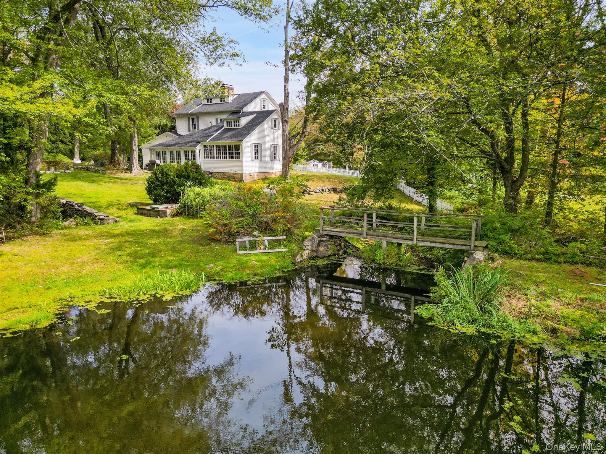 Step into the Past! Rare opportunity to acquire one of Pound Ridge’s finest antiques. Handsome 1784 Colonial, the Horace Reynolds House, renovated by Hiram Halle in the 1930’s. Incredible period details including hand-hewn beams, warm, aged paneling, wide board floors, 9’ ceilings and four fireplaces. Beamed Living Room with fireplace, cooking crane, beehive oven and Parson’s cupboard. Formal Dining Room with decorative fireplace. Private Office/Library overlooking the water. Well-designed Kitchen with Quartz counters, center island, stainless appliances and breakfast area with fireplace. Family Room with French doors and slate floor. Primary Suite with decorative fireplace. Two, potentially three, additional Bedrooms. New Baths. Nearly six gorgeous acres in the heart of the historic hamlet. Over two-acre  pond with dock. Spectacular old stone walls, lovely plantings, rolling lawns and age-old trees. Detached Garage. An incredible offering!