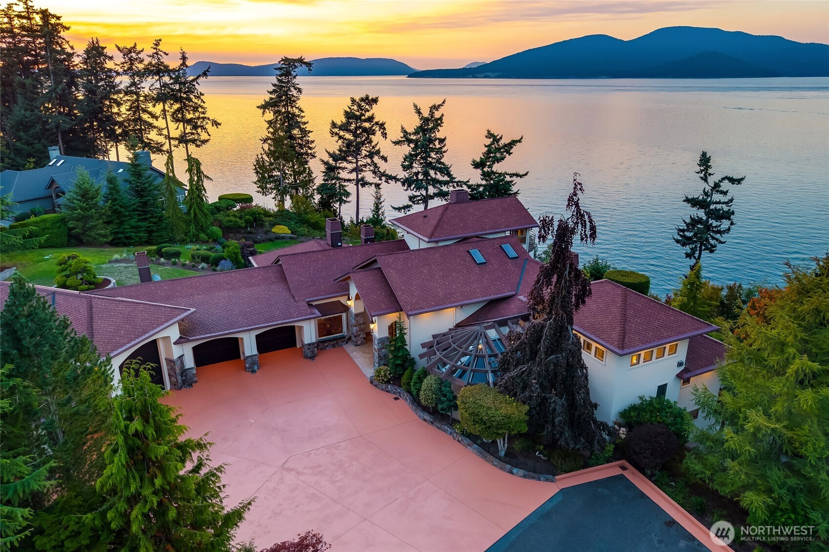 Set on two private acres overlooking the water with direct waterfront access via Guemes Trail, this waterside estate captures 220-degree views across eight islands, the Canadian Coast Mountains, and ferries moving through Thatcher Pass beneath unforgettable sunsets. Thoughtfully remodeled with a focus on architectural distinctiveness and enduring materials, the home balances distinctive design elements with its extraordinary coastal setting. Italian stone surrounds 8 gas fireplaces, with reclaimed European oak ceilings, floors  and beams. Walls of windows frame the changing seascape, bringing natural light and expansive views. The main-level primary suite offers a private retreat with a spacious bath featuring an English copper soaking tub, solarium, fireplace, and reading area.      An elevator connects all levels, leading to an upper private office with an eagle’s-eye view and balcony, and to the lower-level guest quarters and recreation spaces including sauna, exercise room, media room, game room, wine storage, and patios with hot tub. Every room has a water view, even the garage. A wraparound deck spanning three sides offers the perfect vantage point for pink sunrises. Rare tumbled travertine marble appears throughout, plus a heated seven-car garage and separate heated workshop.    A coastal estate where craftsmanship, privacy, and sweeping island views come together in one extraordinary setting.