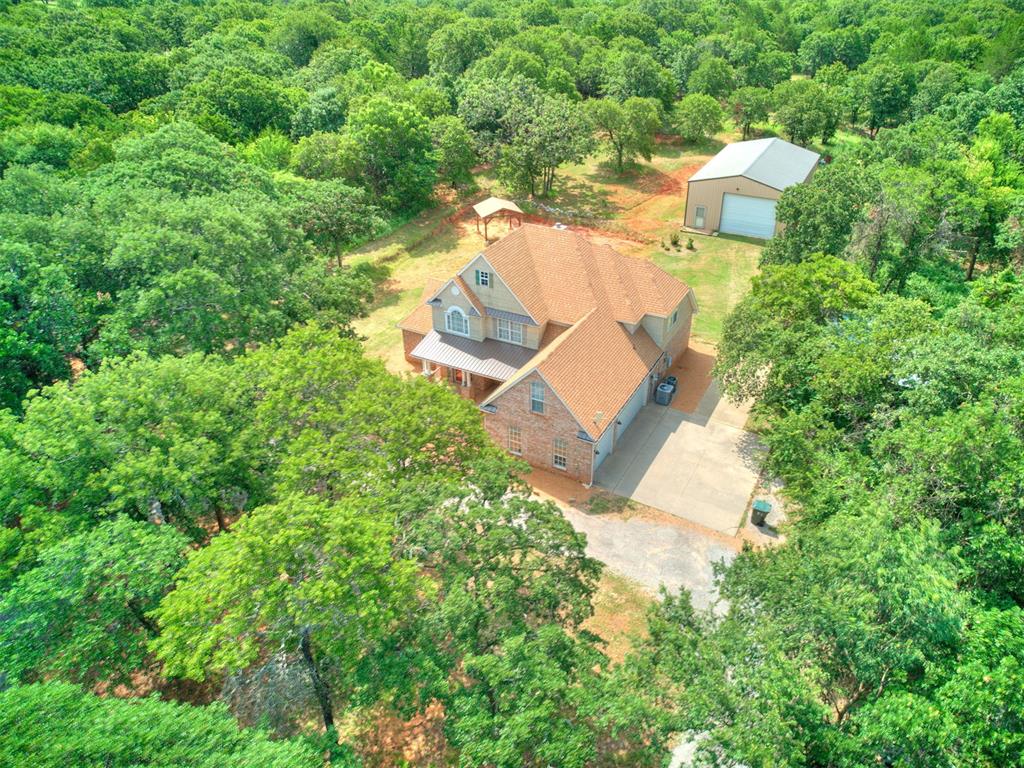 Nestled on five breathtaking acres, this one-of-a-kind property offers privacy and is conveniently just minutes from Norman. Lake Thunderbird is directly across the street; a short 800-foot walk to the shoreline. Inside, find soaring ceilings, rich wood flooring, abundant natural light, and an efficient closed-hearth fireplace capable of heating the home. The spacious kitchen features stainless steel appliances, large pantry, generous cabinet storage, and expansive counter space. A convection oven with radiant cook-top was recently added (2024), making this kitchen as functional as it is beautiful. The private primary suite offers a jetted tub, fully tiled walk- in shower, and spacious closet. Also downstairs, enjoy a formal dinning room and dedicated study (or 4th bedroom) with adjacent full bath. Bedrooms two and three are upstairs with the third full bath. The upstairs is anchored by a spacious loft overlooking the living area (new carpet 2025). Feel secure during severe weather in a bright and large 7'x13' storm shelter beneath the garage floor; just a few dry, protected steps from the living area. Other valued features include triple pane windows, spray-foam roof insulation, insulated garage doors, two-stage water filtration and a water softener. Updates include a new roof (2024), paint, light fixtures, switches and receptacles, and SmartKey door locks. Outside, this property offers endless opportunities. An impressive 30' x 50' insulated shop includes electricity, water, restroom, and large overhead door. An open covered structure provides additional protected storage. Mature trees on the acreage provide exceptional privacy, wonderful shade, and a “lifetime” supply of firewood. Wildlife visits are frequent. You'll enjoy watching deer, turkey, dove, owls, squirrels and rabbits. Horses are permitted. OEC electric and fiber internet. Wow! All this with a Boyd Street address! The numerous features and opportunities of this property make it easy to call HOME~