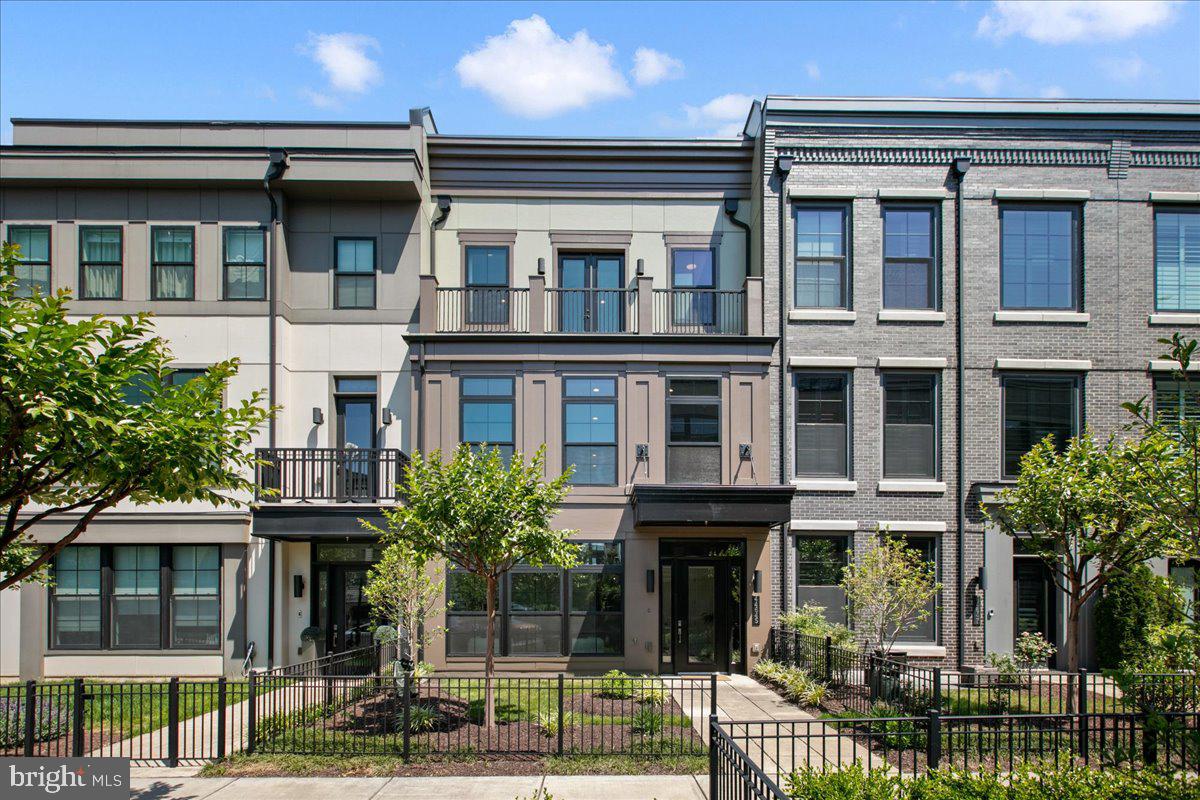 Experience elevated living in this extraordinary 4-level elevator townhome in the heart of highly sought-after One Loudoun. Perfectly positioned on desirable Danvers Terrace with picturesque green space views and breathtaking sunsets, this luxury residence blends sophisticated design, premium finishes, and the convenience of a low-maintenance lifestyle in one of Loudoun County’s most vibrant and walkable communities. One of the most spacious models in the community, the home showcases extensive custom upgrades, exceptional craftsmanship, and elegant modern design throughout.Designed with both sophistication and functionality in mind, the home features impressive 10-foot ceilings, upgraded stunning 7-inch hardwood flooring throughout every level — including all bedrooms — and elevator access servicing all four floors. The entry level offers incredible flexibility with a welcoming vestibule, spacious family room, private office or optional main-level bedroom, powder room with floating vanity, mudroom with custom storage solutions, and access to the rear-load two-car garage. Thoughtful custom details include built-in floating cabinetry in the office, a Scandi entry bench with integrated drawers, and a convenient pocket door enclosure beneath the stairs.The main living level is the true centerpiece of the home, designed for luxurious entertaining and everyday comfort. The chef’s kitchen is a showpiece, featuring premium Wolf and SubZero appliances including a Wolf 6-burner cooktop, convection steam oven, convection oven and microwave, and paneled SubZero refrigerator. Oversized quartz waterfall island, upgraded cabinetry with recessed lighting, walk-in pantry, and designer finishes complete the space. Four Bang & Olufsen ceiling speakers elevate the kitchen experience, while the open-concept layout seamlessly connects the kitchen, dining area, additional powder room with floating vanity and Great Room with gas fireplace, floating shelves, and integrated surround sound speakers. Just off the dining area, enjoy a private balcony perfect for morning coffee or evening relaxation.Retreat to the luxurious primary suite on the third level, where refined finishes create a serene atmosphere. The spa-inspired primary bath features dual sinks in a contemporary floating vanity, soaking tub, and oversized walk-in shower. The custom walk-in closet is truly exceptional with inlaid cabinetry, double-decker felt-lined jewelry drawers, and thoughtfully designed organization. Two additional bedrooms, an elegant full bath, and a well-appointed laundry room with built-in cabinetry, hanging space, and integrated hampers complete this level.The fourth floor offers even more flexible living space with a loft-style entertaining area, fourth bedroom, and full bath with floating vanity. Custom built-in floating cabinetry with hidden remote drawers, surround sound speakers, and premium Haiku ceiling fans create the ultimate retreat. Step outside to the incredible rooftop terrace designed for year-round enjoyment, complete with a gas firepit, stunning sunset views, and expansive outdoor living space perfect for entertaining under the stars.Additional luxury enhancements include upgraded lighting throughout, Restoration Hardware chrome mirrors, premium Haiku ceiling fans, a fully integrated Control4 smart home system expandable for lighting, music, locks, and more, plus POE-enabled wireless access points.Located in the center of One Loudoun, residents enjoy access to premier shopping, dining, entertainment, community events, farmers markets, clubhouse amenities, outdoor pool, tennis courts, trails, parks, and more — all just steps from Trader Joe’s, Barnes & Noble, and Alamo Drafthouse, with easy access to major commuter routes. Minutes to Dulles International Airport and the Washington Commanders practice facility, this exceptional home offers the perfect balance of luxury, convenience, and community living.