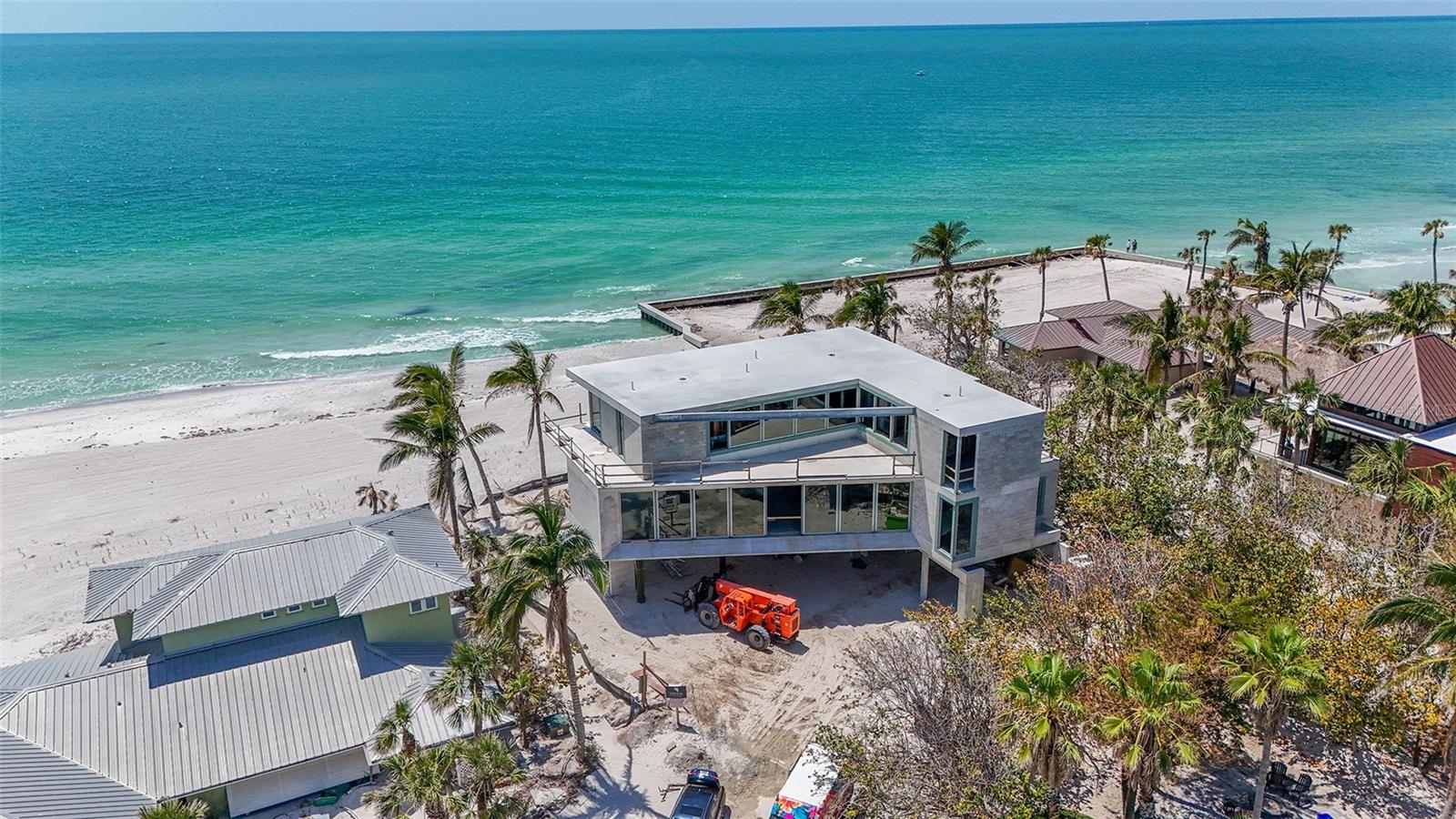 Under Construction. You're in for something special with this new beachfront construction set to be completed by December, 2025. Located on over a quarter acre on Longboat Key, this contemporary luxury home is directly on the beach with stunning Gulf views. Designed with a modern coastal aesthetic, it’s built for both style and comfort. Inside no detail is overlooked. From sleek Walker Zanger porcelain tile to custom cabinetry and polished nickel fixtures, the finishes are top-tier. The gourmet kitchen features an expansive layout with a large waterfall-edge island, double Wolf ovens, Sub-Zero refrigeration, a full-size wine cooler, and a Wolf induction cooktop—everything you need for serious cooking or entertaining. Primary suite is a true showstopper with floor-to-ceiling glass sliders that open wide to a sweeping terrace. Gulf breezes flow through the space, and the shimmering azure water is always in view. Inside, the suite offers a spacious walk-in closet and a spa-like bath featuring tiled walls, a walk-in shower with multiple heads, a soaking tub, dual floating vanities, and a private water closet. Upstairs, an executive office and three generous bedroom suites—each with its own walk-in closet—gives plenty of space for family or guests. A fourth bedroom shares a cozy den, perfect for lounging or movie nights. The grand-level outdoor space takes full advantage of its beachfront setting with a 36-foot lap pool, sun shelf, heated spa, and a fully equipped summer kitchen with a grilling station—ideal for effortless entertaining, all just steps from the sand.
