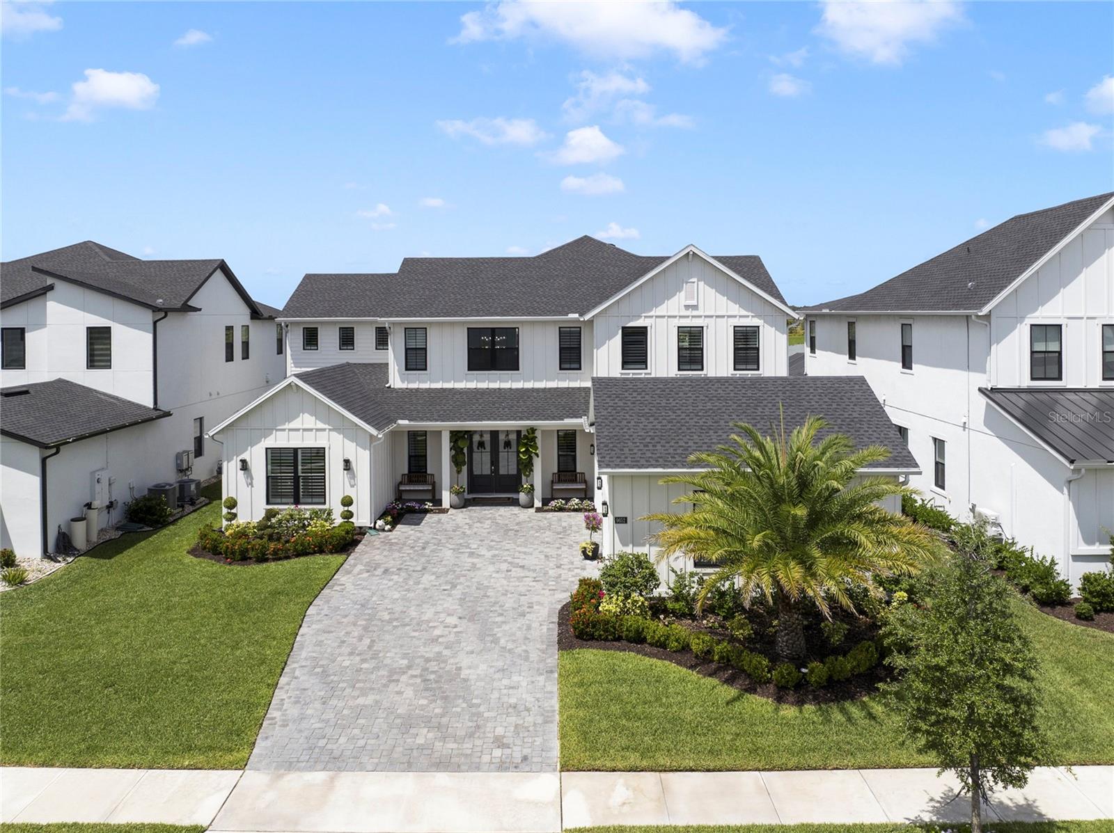 Luxury Living in the Heart of Lake Nona – Designer-Enhanced Estate with Exceptional Upgrades

Welcome to refined elegance and everyday comfort in this meticulously upgraded luxury residence, ideally situated in the sought-after, gated community of Laurel Pointe Lake Nona. Boasting timeless curb appeal with a welcoming covered front porch and grand double-door entry, this home opens to a dramatic two-story foyer with soaring 25-foot ceilings, setting the tone for the spacious and sophisticated layout that unfolds throughout.

The expansive great room features a coffered ceiling, custom wood beams, and a built-in entertainment center with floating exotic wood shelves and a fireplace—perfectly anchored for gatherings or quiet evenings.

At the heart of the home, the chef’s kitchen is a true showpiece. It features an oversized quartz island, natural hand-cut stone backsplash in a striking double herringbone pattern, and a full suite of premium KitchenAid luxury appliances. Solid wood cabinetry with dovetail drawers and soft-close hardware reflects exceptional craftsmanship and timeless quality. The kitchen is further enhanced by a spacious walk-in pantry and a butler’s pantry—blending beauty with function for the ultimate culinary experience. A bright casual dining area offers views of the backyard retreat, making every meal feel special.

The private primary suite on the main level is a true sanctuary, highlighted by custom wood beams, a designer muted gray shiplap accent wall, dual walk-in closets, and a spa-inspired bath featuring a large soaking tub, expansive luxe shower, dual vanities, and a private water closet. A downstairs guest suite offers flexibility and privacy for visitors.

Upstairs, a generous loft with built-in entertainment center and exotic wood floating shelves is surrounded by spacious secondary bedrooms—two with a shared bath and separate vanity areas, one with a hall bath, and one with an en-suite featuring a barn door and cozy window bench. The second primary suite on the second floor offers exceptional space and style, featuring a cedar-accented, herringbone natural stone wall and its own private bath—ideal for multi-generational living or luxurious guest accommodations.

Outdoor Living & Pool Retreat

Step outside into a true resort-style oasis designed for both relaxation and entertaining. The saltwater pool features a PebbleTec finish and is surrounded by elegant white quartz cut stone decking. A thoughtfully designed sun shelf with in-pool loungers invites lazy afternoons, while the sparkling charcoal mosaic tile spa creates a dazzling focal point with room for a crowd.

The self-cleaning pool system adds effortless convenience, complemented by a full cabana bath and a covered lanai with cedar barnboard ceiling and wall accents for added warmth and luxury. Entertain in style with a resort-inspired pergola dressed in flowing curtains, and a built-in outdoor kitchen equipped with a high-end stainless steel Paradise Grill, an oversized stainless range hood, and generous prep space. Retractable electric screens and sunshades create a seamless transition between indoor and outdoor living.
Additional:
Board & batten accent wall in the foyer
Glass barn doors to the flex room/office
Mudroom with custom drop zone
Built-in sound system in kitchen, family room, and lanai
Plantation shutters throughout
Guardian garage flooring with overhead storage
Water softener system
Security system pre-wire
