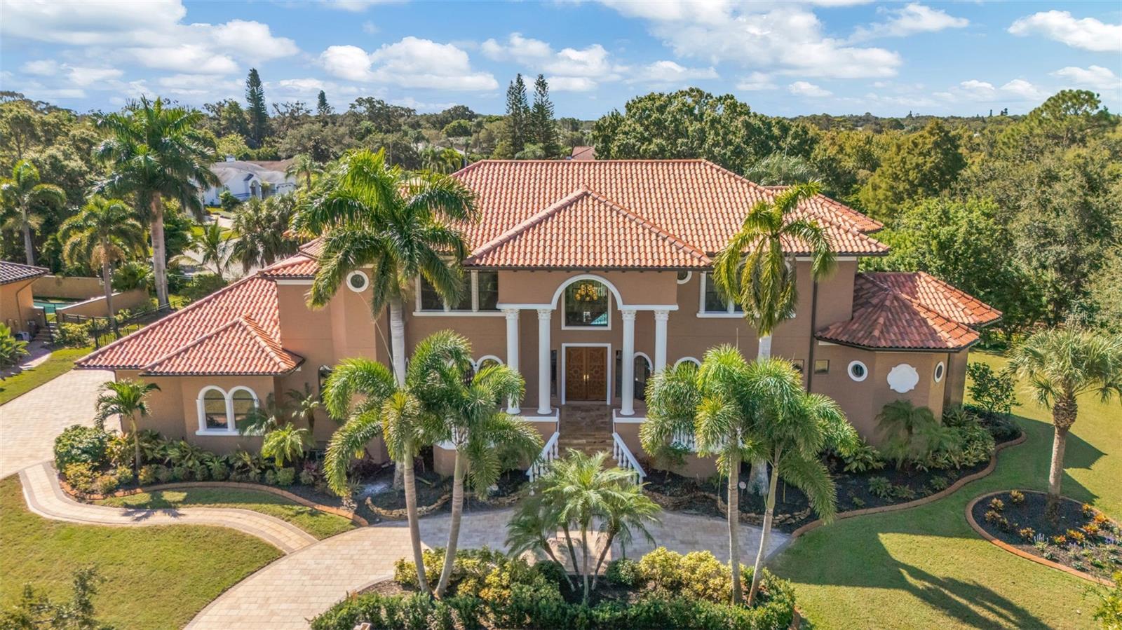 Custom built Mediterranean home with no detail missed in this well thought out design. Lavishly appointed, this elegant home offers four bedroom suites, four full plus two half-baths, game room with wet bar, an office and a three car-garage. The gourmet eat-in kitchen overlooks the family room and features a chef-friendly island, top-of-the-line appliances and granite counters. Soaring ceilings, decorative moldings, two fireplaces and a dramatic, floating staircase are just a few of the amenities. The split bedroom plan includes spacious rooms with large walk-in closets and private baths. Just off the executive office, the master suite with sitting area boasts an incredible master bath with granite floors, glass tile shower, a luxurious hydro/jetted spa,and HUGE walk-in California closet. Entertain poolside at the resort style backyard with full outdoor kitchen! This tropical oasis includes a refreshing pool with remote controlled rock waterfall, full outdoor kitchen, an abundance of lanai space for lounging with surround sound. Sitting on an over-sized 1/2 acre+ fenced lot, this home is conveniently located walking distance  from the local beaches and schools. Never flooded, built high and dry and includes a full house generator!