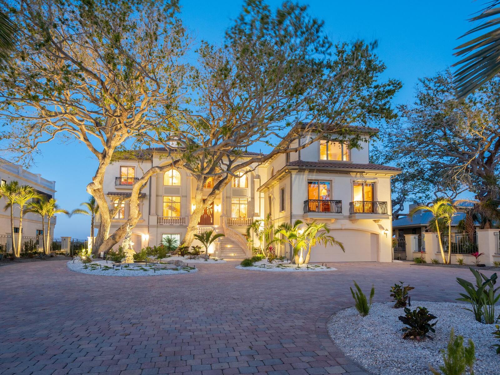 This classically designed estate is privately positioned on north end of Casey Key, considered among the most treasured addresses in Sarasota County. The property spans from a sandy walking beach on the Gulf to a rare covered boat dock on Blackburn Bay. Designed by renowned architect Clifford A. Scholz and built by Delta Southern Construction, over 8,000 square feet designed to celebrate family and guests, this is a residence that inspire togetherness and embodies the art of waterfront living. Crafted with luxury finishes and modern conveniences, the property is built to exacting coastal standards with dramatic focus on stunning water views. Formal and casual spaces unite elegantly, including the living room with cypress beamed ceilings, overlooking the bay. A deluxe kitchen, wine, butler’s pantry and wet bar provide a canvas for culinary exploration and entertaining elegance. A grand media room for screening films provides the ideal place to unite music and culture. The expansive primary bedroom features a sitting room, lavish bath, dual closets, a breakfast nook and expansive views over the water. Three additional bedroom suites provide privacy, views and spacious accommodations. The fifth bedroom suite is equipped for a home gym, steam room and sauna. The office and library, next to the grand marble staircase, features leaded glass doors, hand crafted, built-in shelving, a coffered ceiling and beautiful views of the Gulf. Additional space for recreation and relaxation has been accomplished to make use of every inch of the estate. Arched hallways and French doors line the living room, open to the dazzling outdoor spaces and stone terraces lead to the infinity pool. Elevator access and garages for six vehicles add ultimate convenience. Enjoy boating from the deep-water dock which features a rare and grandfathered-in covered boat lift. North Casey Key is a haven of exclusivity and serenity, minutes from shopping, world-class golf, tennis and dining.