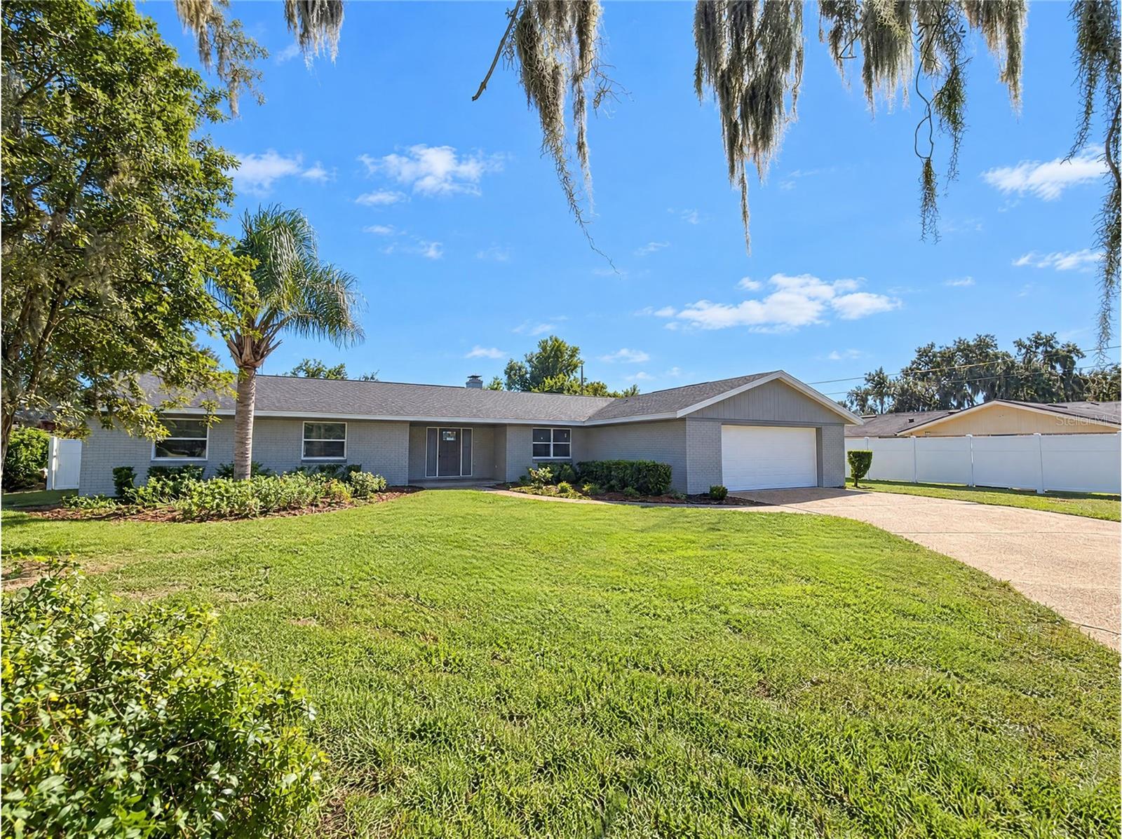 2160 De Las Flores Ave is a single-story Bartow home with three bedrooms, two full bathrooms, a half bathroom and over 2,000 sq ft of living space. An island anchors the kitchen, which opens to the dining area and adjoining living spaces. A central fireplace wall separates the living areas, and a bay-window breakfast nook sits beside the kitchen. Sliding glass doors lead to a screened porch overlooking the backyard. The primary bedroom has an adjoining bathroom, while the hall bathroom includes dual sinks and a tub-shower combination. A laundry room with a utility sink and an attached two-car garage complete the layout. Included 100-Day Home Warranty with buyer activation
