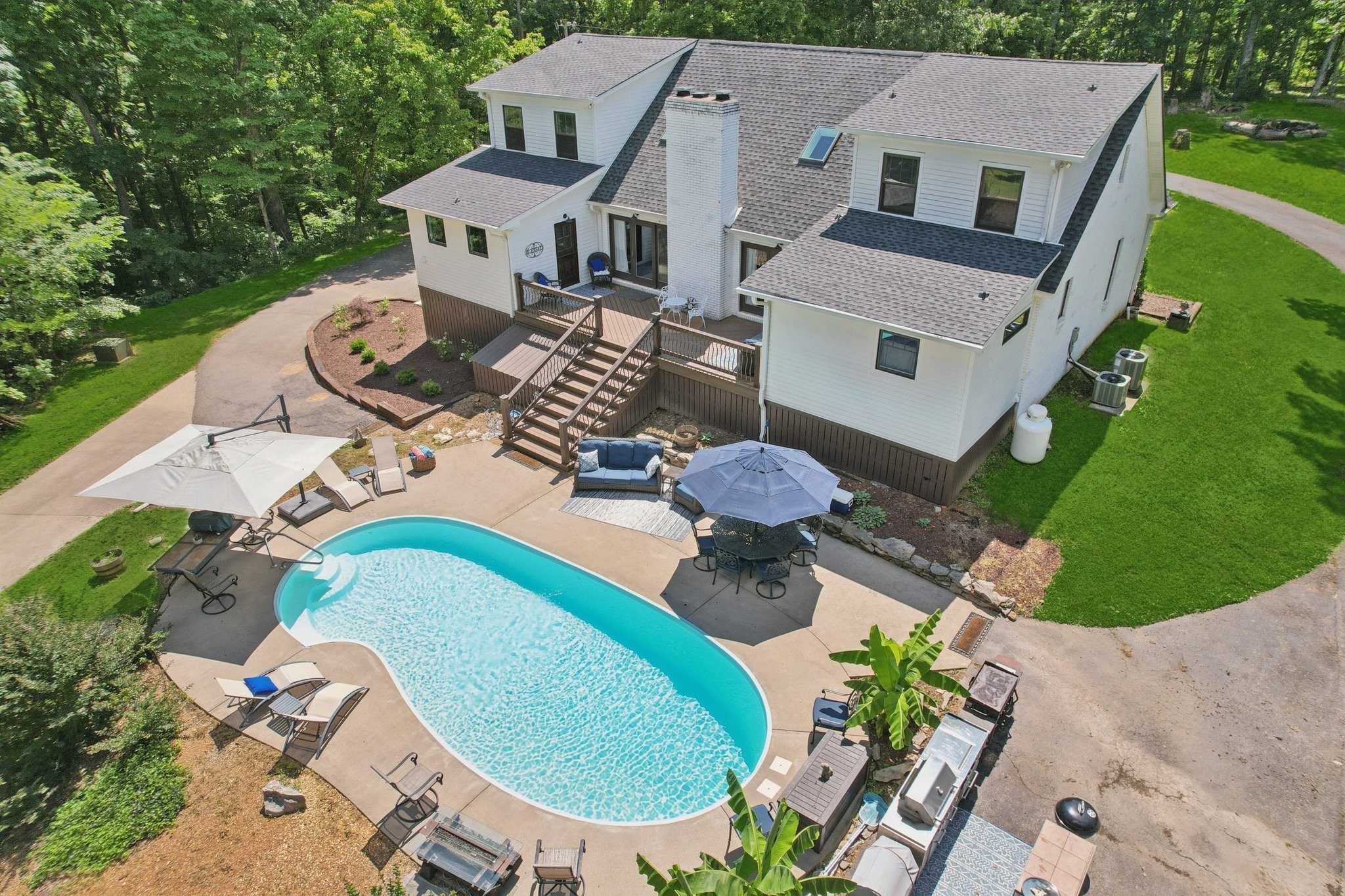 Not your typical Clarksville property!! PRIVATE, wooded multi-generational or income producing property with over 6,923 sq ft of living space in TWO HOMES sitting on over 25 acres! REMODELED Main House with 3 bedrooms, 4.5 baths & finished basement with INGROUND POOL & large DETACHED GARAGE/WORKSHOP plus a spacious 4 bedroom, 2 bath Guest House! The main house has 3 levels of living space and has been completely renovated for a luxurious but comfortable home! Handcrafted Custom cabinetry and doors! Primary Suite offers a vaulted ceiling and luxurious bathroom area with 2 huge walk-in closets, dual rain head tile shower, double vanities with custom cabinets, linen closet, and a soaking tub large enough for a tall person to enjoy a soak! You'll love the Gourmet custom designed kitchen with stainless appliances, tons of granite countertop space & bar area, double ovens, farmhouse sink, coffee bar space & large 6 burner gas stove w/grill! The Laundry area off the kitchen has a HUGE walk-in pantry & tile pet washing station! The 2nd story balcony overlooks the comfortable living/kitchen/dining area with fireplace that's situated in the middle of the house with double sliding doors that exit to the large deck & relaxing inground pool area on the back of the home! 2 bedrooms w/full baths upstairs and finished basement with another room, full bath & rec room downstairs! Behind the Main House, you'll find the 2nd home with 4 BR, 2 BA (ADA compliant), large covered front porch with private deck area on each end of the house & a 3 c garage! The living room, kitchen & sunroom are conveniently located in the middle of the house and is perfect for in-law quarters or additional family members or guests! The HUGE detached garage/workshop structure is tall enough for larger vehicles like RV's or tall trucks or boats and has plenty of built-in shelving & a workbench making it the perfect place to work on vehicles, store lawn equipment or all the outdoor toys!