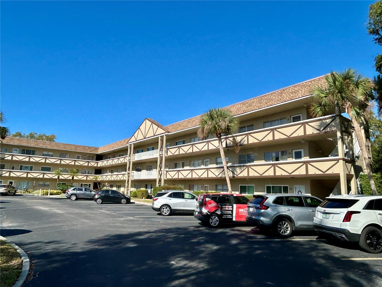 Silence is golden! Enjoy the peace and serenity of this top floor, 2 bed, 2 bath end unit situated on a quiet cul-de-sac overlooking a park-like setting of trees and greenery. This end unit has additional windows in the living room and kitchen to let the daylight in. The kitchen includes an updated dishwasher and refrigerator. The AC was replaced in 2019. New PGT windows scheduled to be installed January, 2026, with transferrable warranty to new owner. Enjoy the convenience of your assigned parking space. Located in a vibrant 55+ community, you'll have access to a wide range of amenities designed to enhance your lifestyle. Enjoy two private golf courses (9 and 18 holes), two heated swimming pools, and two activity centers. Stay active in the remodeled cardio gym or engage in various community activities like fitness classes, dancing, clubs, cards, and billiards. Pet owners will love the pet-friendly environment, featuring a fenced dog park and covered seating areas. Residents can also enjoy hobby studios and a woodshop for creative pursuits. The on-site Good Karma Café offers convenient 'take & bake' meals and snacks. Conveniently located near beaches, transportation, shopping, entertainment, and fine dining. Schedule your showing today and enjoy the best in comfort and convenient living!