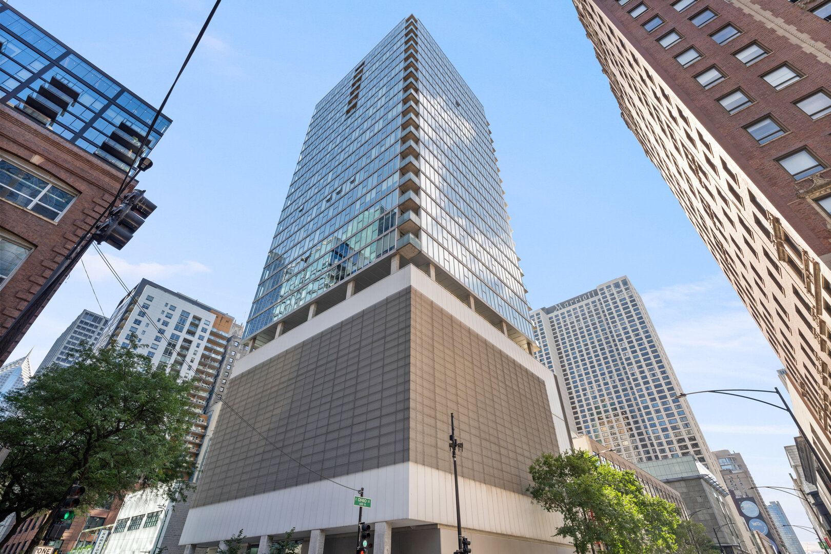 Designed by the acclaimed architecture firm Brininstool + Lynch, this custom half-floor residence spans 3,200 SF with 3 bedrooms and 3 bathrooms. Nearly 50 feet of west-facing floor-to-ceiling windows are flanked by a 300-square-foot terrace capturing Michigan Avenue and dramatic skyline views, pairing sleek architecture with incomparable scenery and elevated finishes throughout.  Light-filled and expansive, the home features 11-foot ceilings, wide-plank oak floors, premium window treatments, and an abundance of storage throughout. The gourmet kitchen, positioned in the southwest corner of the residence to maximize natural light and sweeping city views, offers an oversized island with breakfast bar, Wolf/Rohl/Sub-Zero/Bosch appliances, and custom cabinetry with a timeless subway tile backsplash. A spectacular butler's pantry/second kitchen extends the space with an additional oven, microwave, stovetop, and wine and beverage refrigeration, offering both style and functionality. At the heart of the entertaining area, a custom-designed, temperature-controlled 600-bottle wine cellar enclosed in glass serves as both a centerpiece and a true collector's amenity.  The primary suite is a serene sanctuary, offering a gracious sitting area with a cozy fireplace and a private balcony. An extraordinary 19' x 11' dressing room provides boutique-style wardrobe storage, while the spa-inspired bath includes dual vanities, an oversized glass-enclosed shower, and a deep soaking tub perfectly positioned for sparkling city and lake perspectives. Thoughtful finishes and vast proportions elevate the suite into a genuine retreat.  Two additional bedrooms each enjoy an en-suite full bath and frame postcard views of the Chicago Tribune Tower's crown, creating luxurious private quarters for guests or family. Daily living is made effortless by an oversized mudroom with custom built-ins and a farmhouse sink, ideal for organized, grab-and-go city life.  This residence balances vast, open spaces with a highly functional layout, designed for both quiet everyday moments and sophisticated entertaining. Outside your door, enjoy Michigan Avenue shopping and, just a few blocks south, direct access to the 1.25-mile Chicago Riverwalk - a vibrant promenade of restaurants, boating activities, cafes, and wineries.  Two premier heated parking spaces are included. The full-service luxury building offers 24-hour door staff, a fitness center, indoor pool, sundeck, and more - placing you moments from the lake, the Mag Mile, and Chicago's best culture and cuisine.
