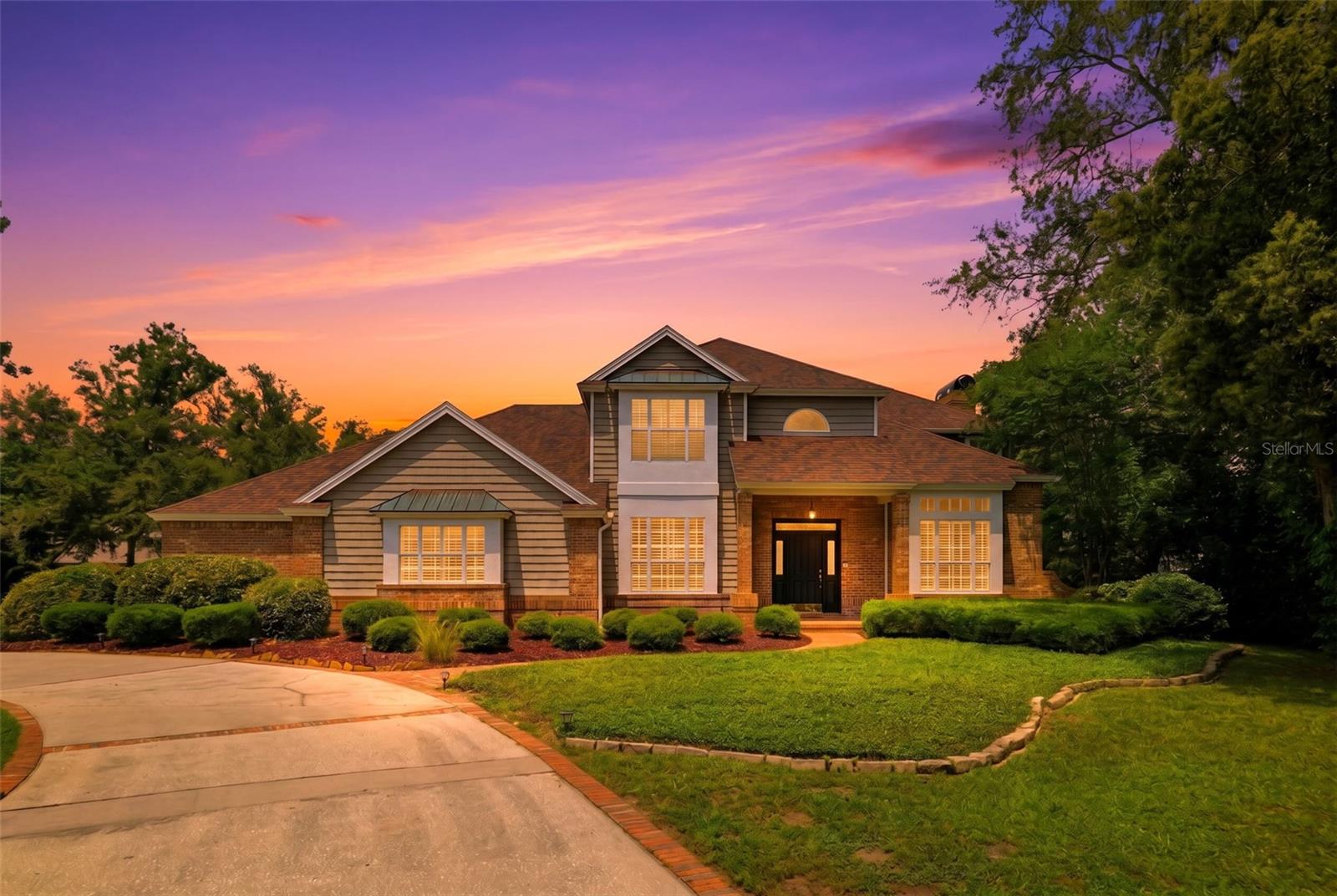 Tucked behind the gates of sought-after Gracewood at River Ridge, this impressive custom home blends timeless character with exceptional craftsmanship. From the circular driveway and antique brick façade to the charming copper roof accents, every detail makes a lasting first impression. Inside, a dramatic double staircase creates a stunning focal point in the welcoming foyer, leading into a thoughtfully designed layout with expansive living spaces ideal for both everyday living and entertaining. Step outside to your screened pool oasis featuring a stunning travertine deck, covered lanai, and plenty of room to relax or entertain year-round. Storage is abundant throughout the home with multiple closets, pantries, walk-in attic space, and an oversized garage with built-in storage and workspace. Gracewood at River Ridge offers a tranquil, private setting while remaining convenient to shopping, dining, golf, and more. This one-of-a-kind home is a must see!