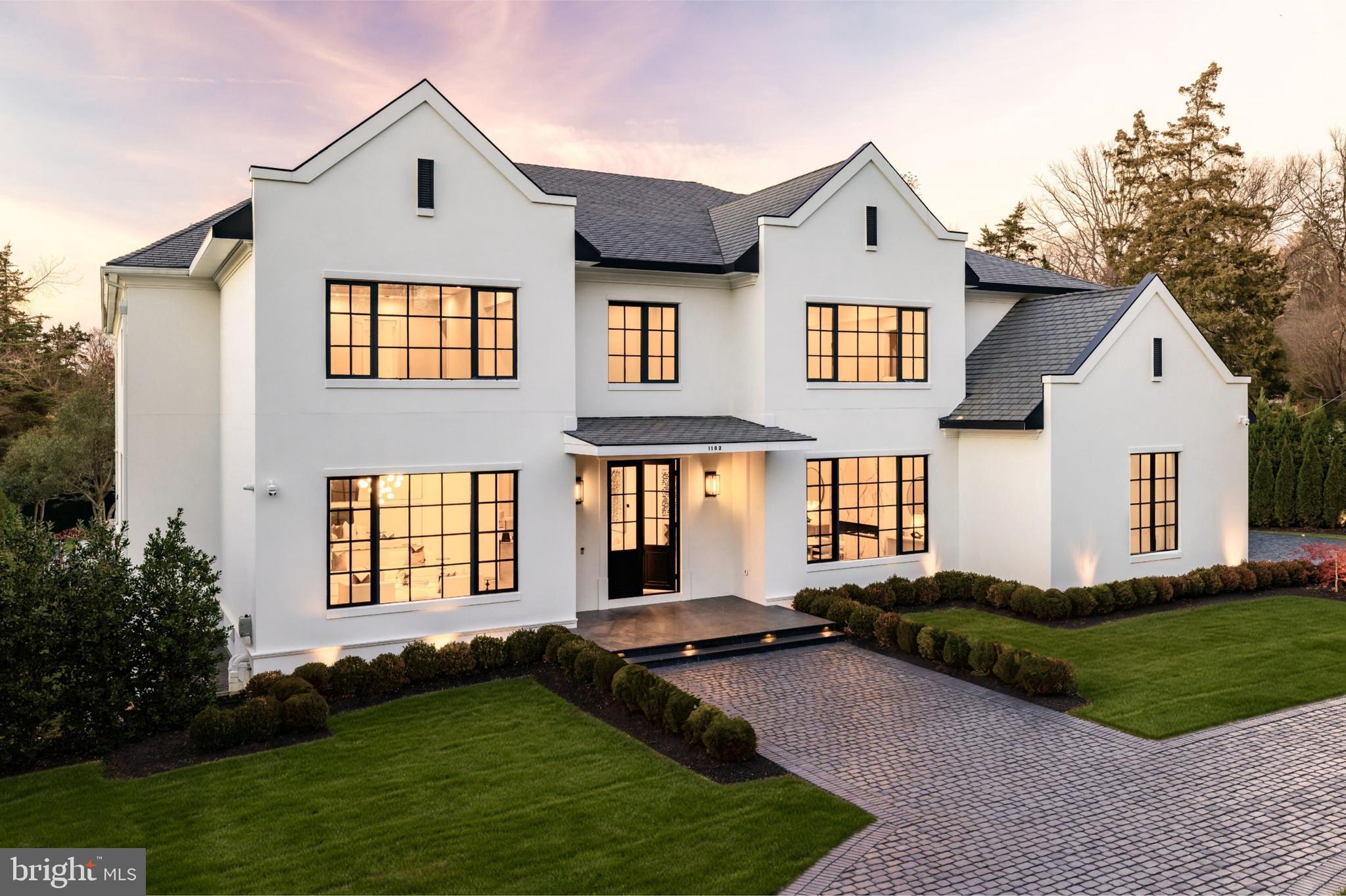 A new crown jewel in McLean, developed by Ambar, 1102 Chain Bridge Road commands attention in the prestigious Langley Farms enclave. A newly constructed triumph that fuses contemporary elegance with transitional château attributes, this estate is tailored for the digital age yet crafted with an artisanal touch seldom seen today. Spanning over 16,000 square feet, it is a showcase of forward-thinking design and enduring craftsmanship.Set on a rare 0.8-acre lot, the approach reveals a gracious cobblestone motor court enveloped by sleek, mature privacy landscaping. Beyond grand double doors, a herringbone-floored foyer offers clear sightlines through the home’s depth, introducing 12-foot ceilings, solid walnut floating stairs, and 10-foot custom wood doors with Emtek hardware. These are testaments to the home's exacting attention to detail. Wide-plank engineered floors and recessed crown uplighting provide a refined warmth throughout.Designed equally for grand entertaining and everyday comfort, the main level flows effortlessly between formal and informal spaces. At its center is an aspirational chef’s kitchen: dual waterfall islands clad in Spanish marble, Italian composite cabinetry, a vintage Viking 8-burner range, and a full Miele suite. A separate, fully enclosed spice kitchen with its own Miele appliances adds further versatility.Three floor-to-ceiling collapsible glass walls open to reveal true indoor/outdoor resort living. A covered patio offers ideal al fresco dining, while the marble terrace introduces a stunning heated lap pool with spa, waterfall, hidden drainage, and an automatic cover. A private guest suite with direct patio access and panoramic pool views is quietly tucked away on the main level.Upstairs, the primary suite is a sanctuary of serenity. Beyond a long corridor and double doors lies a generous sleeping room and private sitting area, divided by a custom linear fireplace. Two sets of French doors open to a private terrace with sweeping views. The spa-inspired bath is clad in Dekton and features radiant heated floors, eight shower heads, a Kallista soaking tub, dual water closets, and separate his-and-hers dressing rooms outfitted in custom Italian cabinetry with illuminated glass displays and center islands.Additional upper-level bedrooms are grand in scale, each with tray ceilings, custom walk-in closets, and designer en suite baths. A convertible nursery offers discreet access to the primary suite. A spacious laundry room with dual islands and full-height cabinetry completes the upper level.The lower level is designed for elevated recreation and wellness. Amenities include a professional home cinema, a full bar with a Dekton island, and a fireside lounge wrapped in Porcelanosa tile. A secure safe room with 36-inch concrete walls and a Fort Knox vault door offers peace of mind. The wellness wing is a true retreat, with a steam shower, commercial sauna, fitness studio, and walk-up access to the outdoors.Engineered for longevity and performance, the home features a commercial-grade elevator, 600-amp electrical service, copper plumbing, five Carrier HVAC zones, and dual 80-gallon water heaters. Infrastructure is in place for a full-house gas generator. A central security suite monitors the 8-camera system, while a sophisticated URC system provides integrated control of Lutron lighting and concealed surround sound via in-wall iPads and smartphones.The 54-foot four-car garage with soaring ceilings is a dream for the automobile enthusiast. Meticulous landscaping and artful hardscaping unify the estate’s bold presence with its refined aesthetic. With commanding architecture and an unrivaled array of modern amenities, 1102 Chain Bridge Road stands as one of the Capital Region’s most exceptional residential offerings.