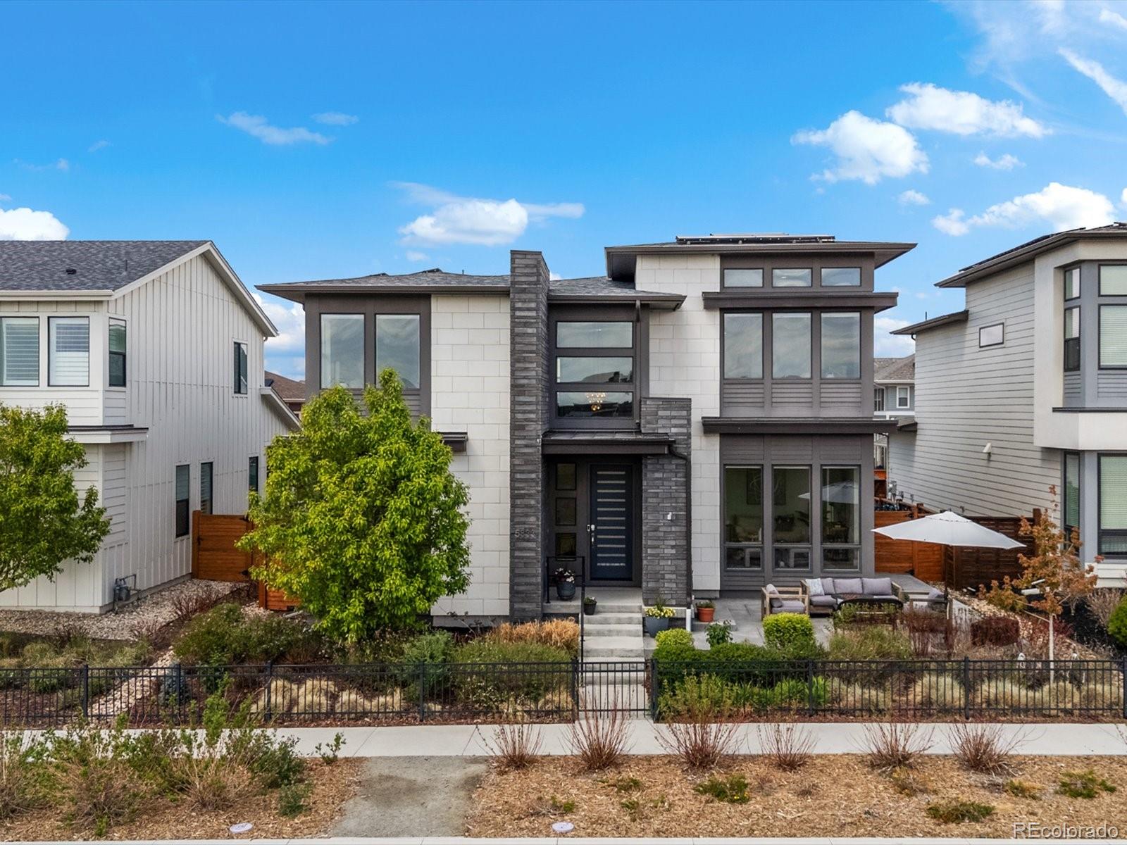 Set on an oversized south-facing lot directly across from 8 acres of green space, this highly upgraded Infinity Vive 1 offers a rare blend of striking design, thoughtful customization, and exceptional energy efficiency, complete with an owned solar array. A serene front patio welcomes you in, leading to a dramatic two-story entry where Restoration Hardware lighting, wide-plank oak engineered flooring, and expansive 8-foot windows set the tone for the home’s elevated yet livable design. A dedicated main-floor office with mountain views provides an inspiring work-from-home space, while the light-filled living room anchors the open-concept layout. The chef’s kitchen features a herringbone Carrera marble backsplash, soft-close cabinetry, an oversized island with quartz counters, and top-tier appliances, complemented by a custom walk-in butler’s pantry. The kitchen flows into the dining area and out through stacked Pella sliding doors to a landscaped backyard and extended patio, perfect for indoor-outdoor living. A mudroom connects to the 2-car garage with Level 2 EV charger and a 3-car driveway spot for added parking. Upstairs, a loft leads to the primary suite, showcasing 12-foot ceilings, expansive views, a designer accent wall, and double walk-in closets. The spa-like bath includes dual vanities and a frameless glass shower with dual shower heads. Three additional bedrooms, one with an en-suite bath, plus a full bath and laundry room complete the upper level. The finished basement expands the home’s versatility with a large secondary living space, a fifth bedroom, a walk-in shower bath, and a finished storage room. Ideally located within walking distance to Splash Landing Pool, Pearl Market, parks, trails, and open space, this home offers a seamless combination of design, efficiency, and prime Central Park living.