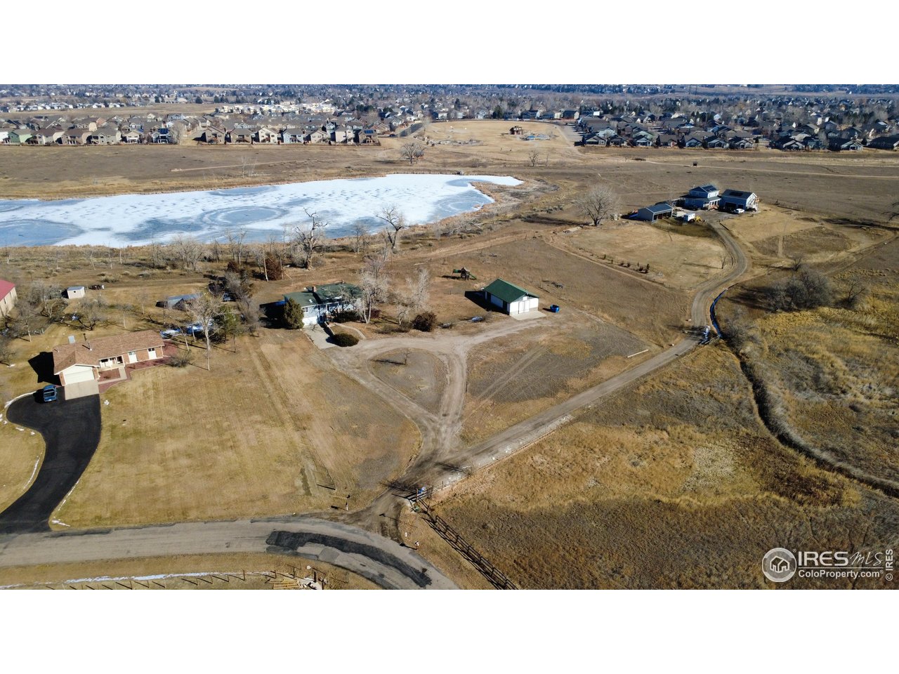 Lake views, Updated Home, Shop and a Prime NOCO location! Enjoy sweeping lake views from this 2.5-acre lakefront home primed to be your hobby farm or horse property. The open, light-filled home features vaulted ceilings, a remodeled kitchen and main bath w clawfoot tub, finished garden-level basement, oversized attached garage, and a 1,064 SF powered shop. Ideally located and no HOA. The interior is designed for both function and connection to the outdoors, with skylights, wrapped beams, and multiple outdoor access points that highlight the surrounding views. The remodeled kitchen includes solid-surface countertops, stainless appliances, a 5-burner gas range, deep undermount sink, built-in pantry, and an oversized eat-in peninsula well-suited for everyday living or entertaining. Living and dining areas offer generous proportions, fireplace features, and direct access to covered and side porches. Main-level bedrooms provide flexible use, including a third bedroom with built-in desk and cabinetry ideal for office needs. The finished garden-level basement expands usable space with a large family, gym, or flex area, fireplace, bonus room with exterior access, additional bedroom (nonconforming), full bath, storage, and mechanical areas. An oversized attached garage adds convenience with interior basement access.The detached ~1,064 SF shop/outbuilding with concrete floor and separate sub-panel supports workshop, storage, or equipment needs. With usable acreage, scenic lake views, and a central location offering straightforward access to regional amenities and commuter routes, this property combines lifestyle flexibility with everyday practicality. Seller offering $25,000 for Buyer Improvements, including Roof estimate of $16k (or it can be replaced prior to Closing).
