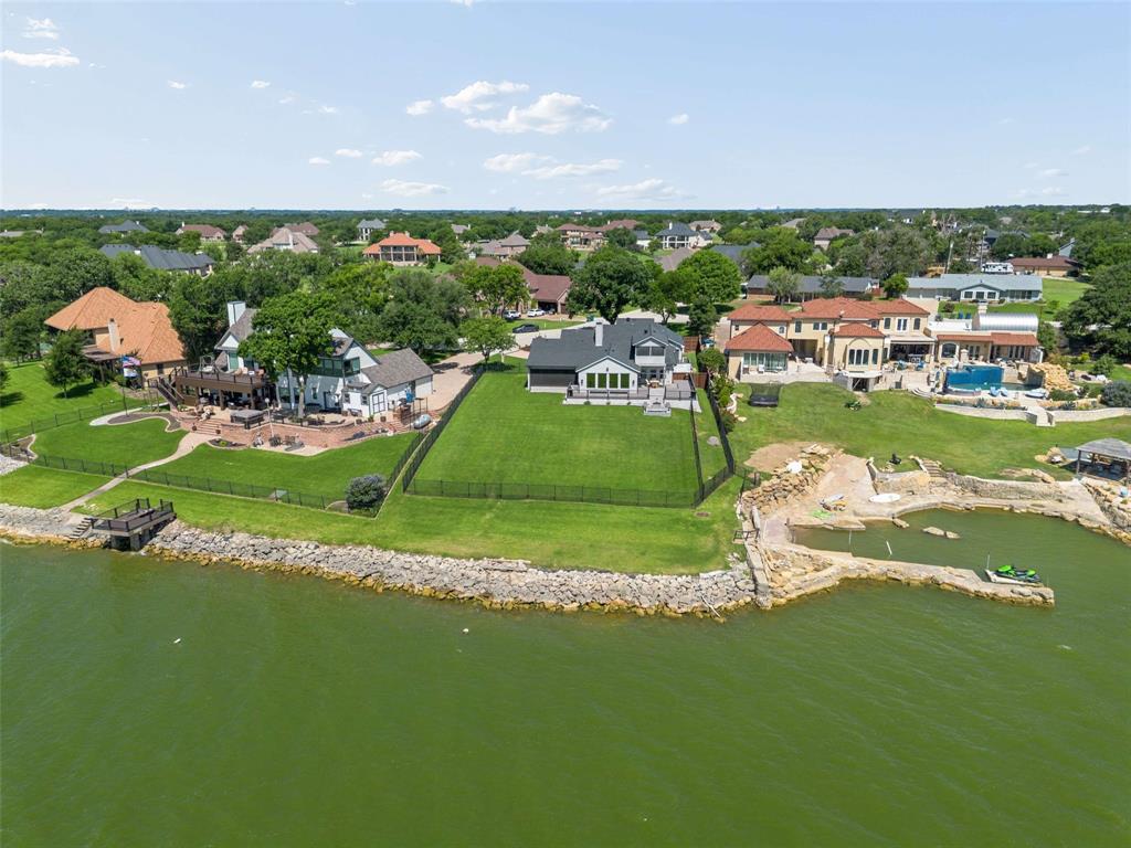 Experience exceptional waterfront living in the highly sought-after community of Lakewood Village on the shores of Lewisville Lake. Situated on a beautifully maintained lot with stunning water views, this is a rare opportunity to enjoy lake living just minutes from Frisco, Little Elm, Denton, and the DFW Metroplex.Completely remodeled and expanded in 2018, this home blends modern comfort with timeless lake house charm. Every improvement was thoughtfully designed to maximize both functionality and the incredible waterfront setting.Enjoy beautifully maintained landscaping and multiple outdoor living spaces, including a screened porch, a second-story screened balcony with panoramic lake views, and a new deck with built-in lighting and drink rails. Relax around the stone fire pit with accent lighting or take advantage of the opportunity to construct your own private shoreline deck, subject to the required shoreline approvals, creating the perfect place to enjoy the lake.Inside, the home features a whole-home audio video system, Sonos speakers, automated window coverings, a security system with exterior cameras, a two-stage zoned HVAC system, and an oversized six-foot Jacuzzi tub with heater and interchangeable lighting. Additional amenities include a garage storm shelter, French drainage system, EV outlet, dedicated dog run with its own deck, lake-fed sprinkler system, Christmas lighting outlets, and a powerful backyard security light.Lakewood Village is known for its spacious homesites, mature trees, and peaceful waterfront setting. With convenient access to boating, fishing, and recreation on Lewisville Lake, it offers one of North Texas' most desirable lakefront lifestyles.Whether you're looking for a full-time residence or weekend retreat, this exceptional property combines luxury, outdoor living, breathtaking lake views, and the potential to add a private shoreline deck for the ultimate waterfront experience.