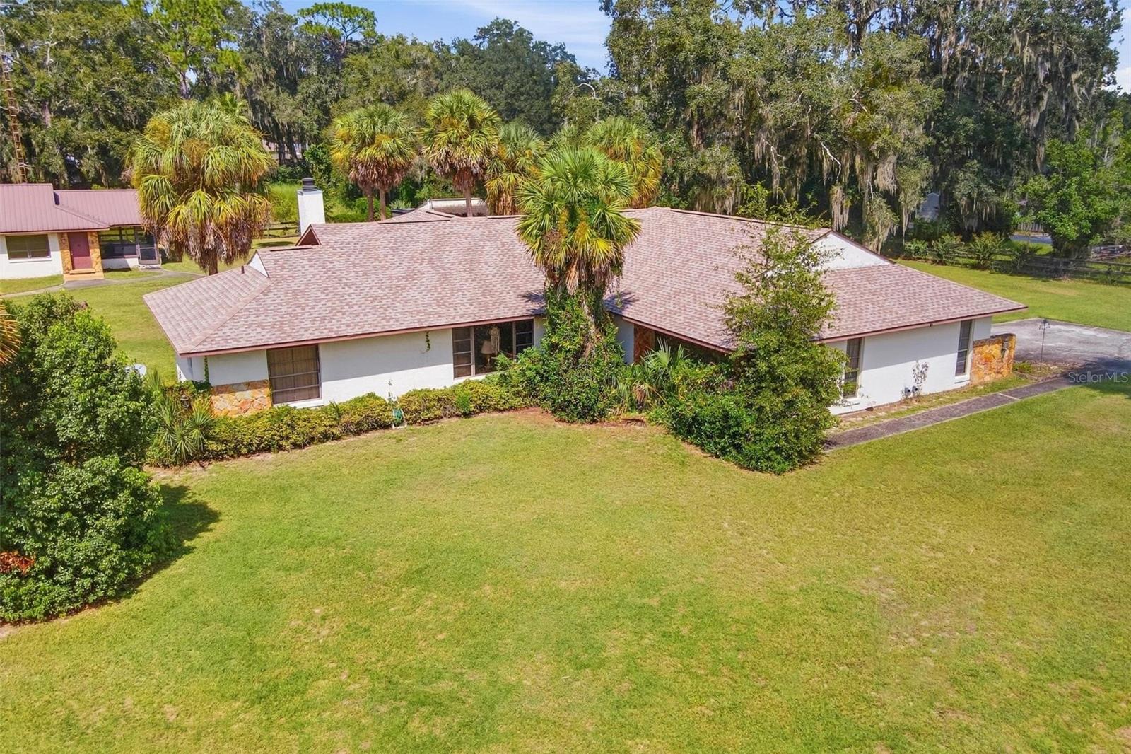 Room to Roam! Situated on approximately 2.27 fully fenced acres in Bridle Trail Estates, this property offers a flexible setup with a 2-bedroom, 2-bath main residence ( 2,114 sq ft), separate 1-bedroom, 1-bath guest house ( 980 sq/ft), and barn with two horse stalls. The main home features two bedrooms arranged as private suites, along with a spacious screened porch and vaulted ceilings with cedar detailing. A new roof was installed on the main house in 2026. The separate guest house provides its own driveway, full kitchen, living area, bedroom, bath, and screened porch, making it well suited for extended family, guests, or a variety of additional living arrangements. The guest house has a 2013 metal roof. Outside, the property is completely fenced and includes a barn with two horse stalls, offering plenty of room for animals, hobbies, or additional storage. The home is ready for updating and provides an opportunity for a buyer to renovate and personalize the property to their own taste, while taking advantage of the acreage, multiple living spaces, and unique layout.
